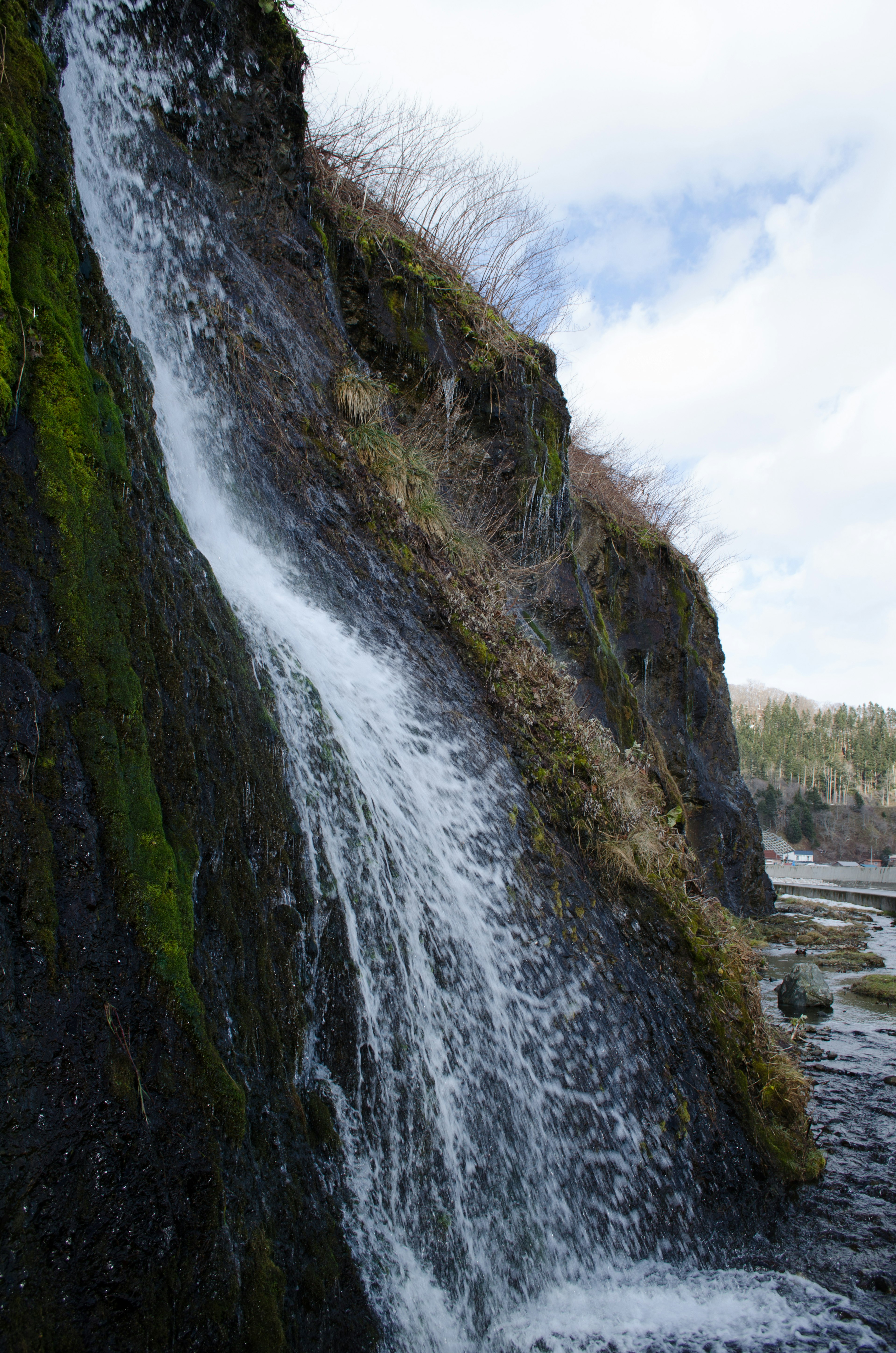 Schöne Szene eines Wasserfalls, der über einen moosbedeckten Felsen fließt