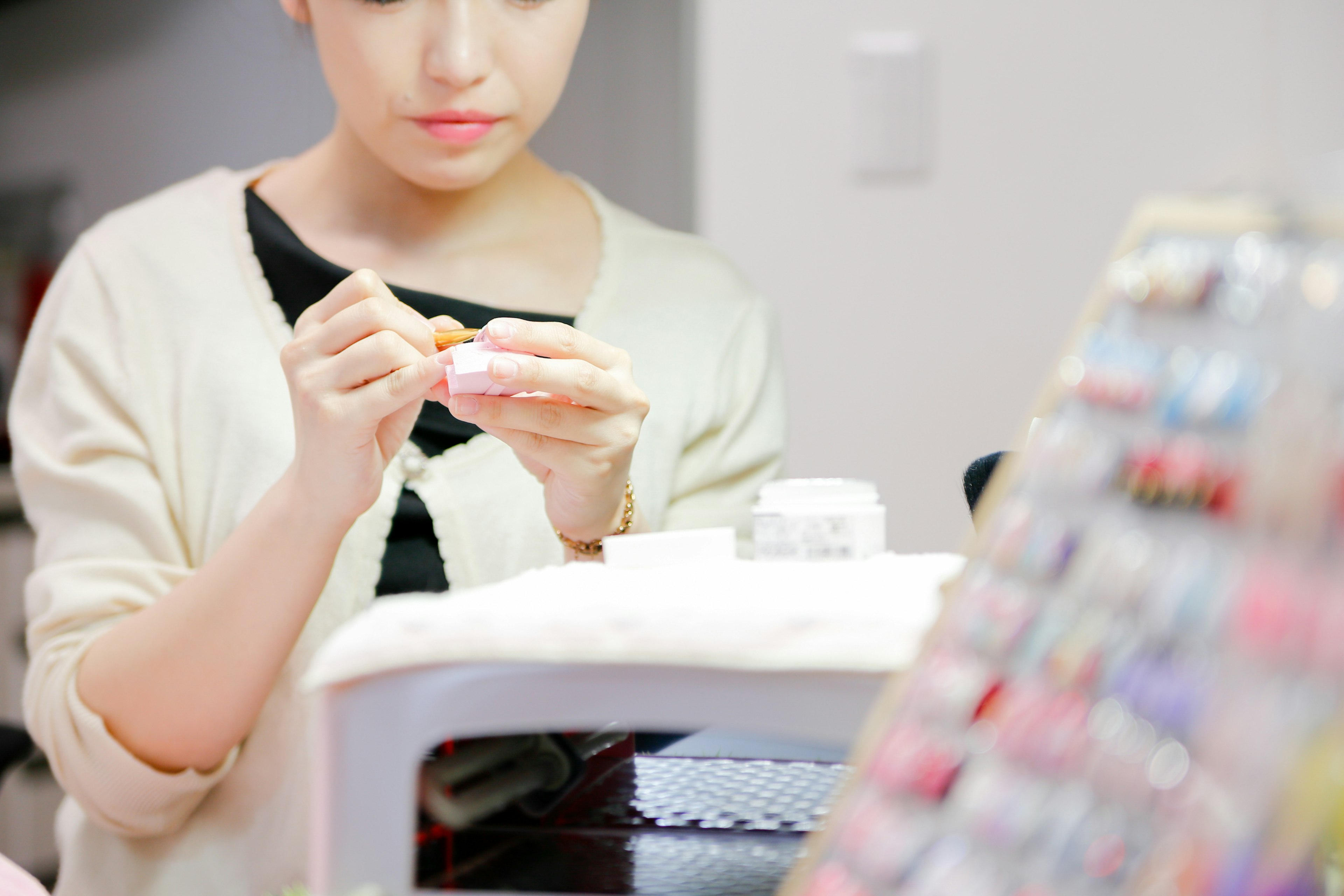 A woman holding a small container for nail art application