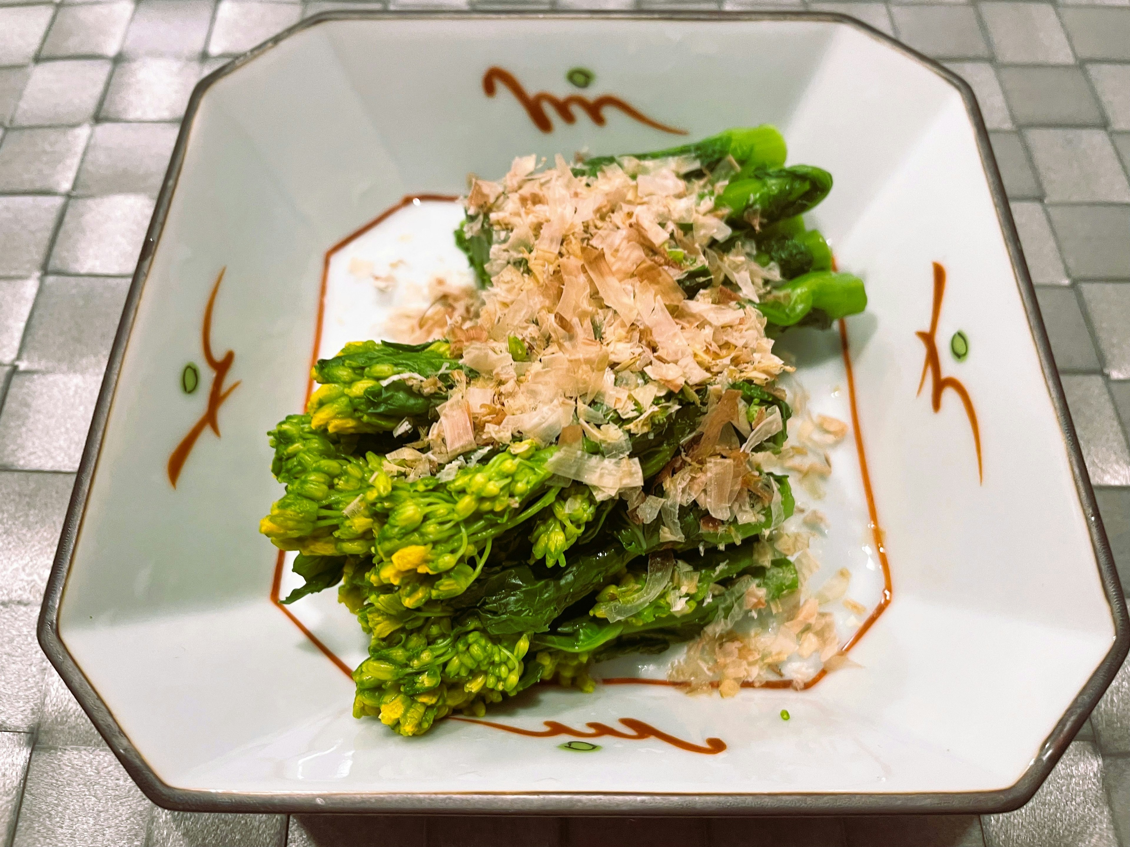 Asparagus topped with bonito flakes served in a decorative dish