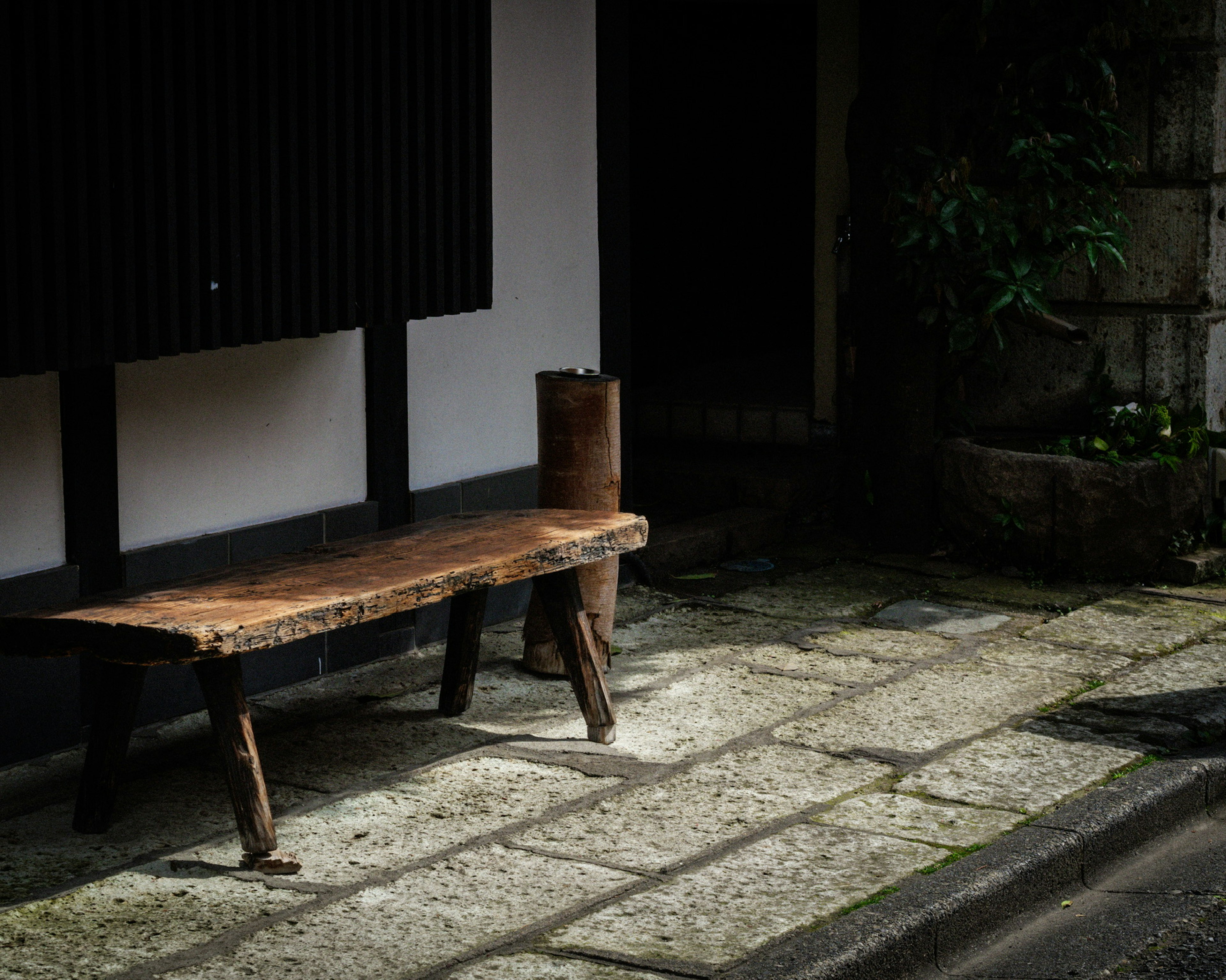 古い木製のベンチが石畳の上に置かれている静かな風景