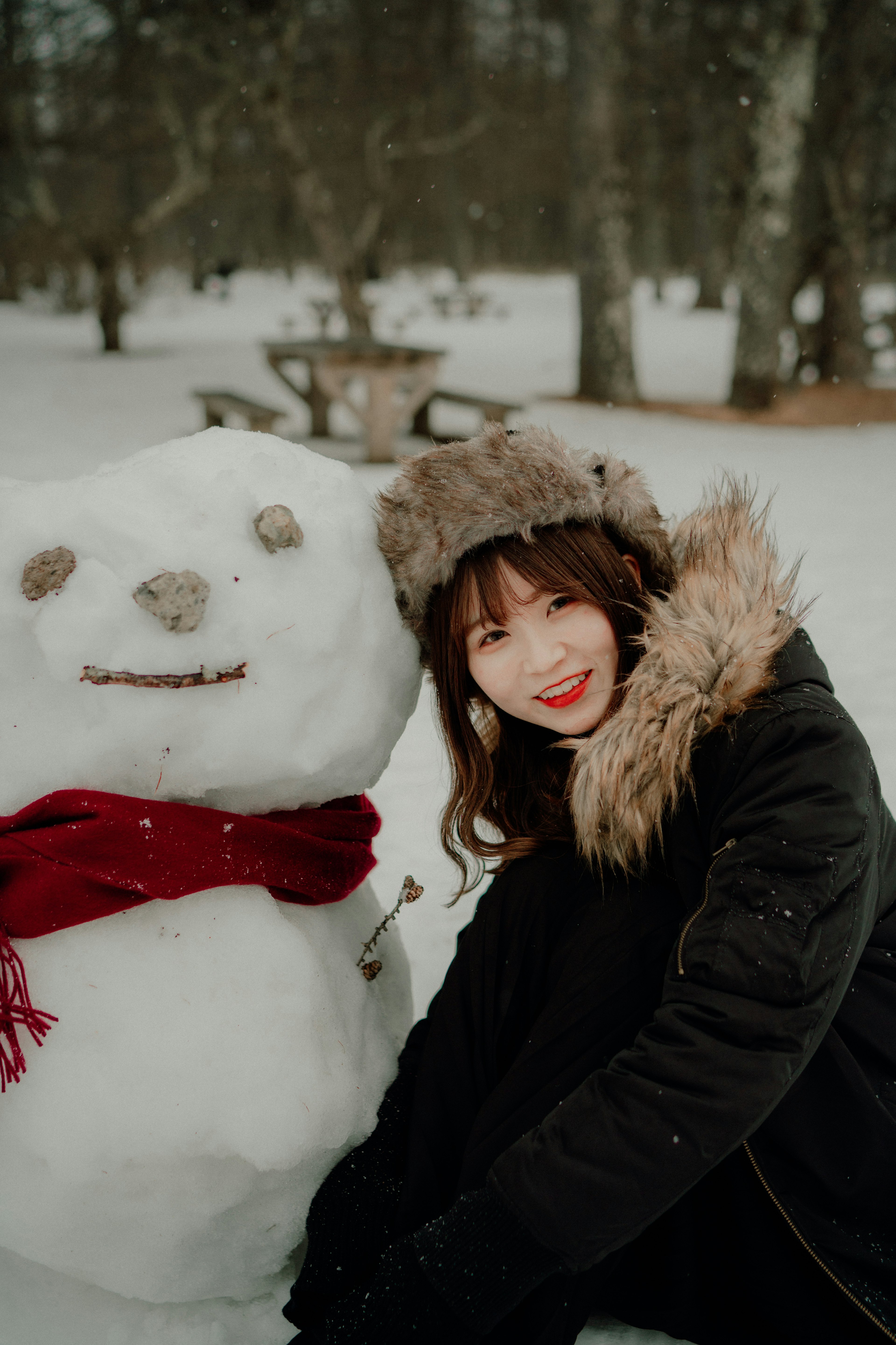 Une femme souriant à côté d'un bonhomme de neige dans un paysage enneigé