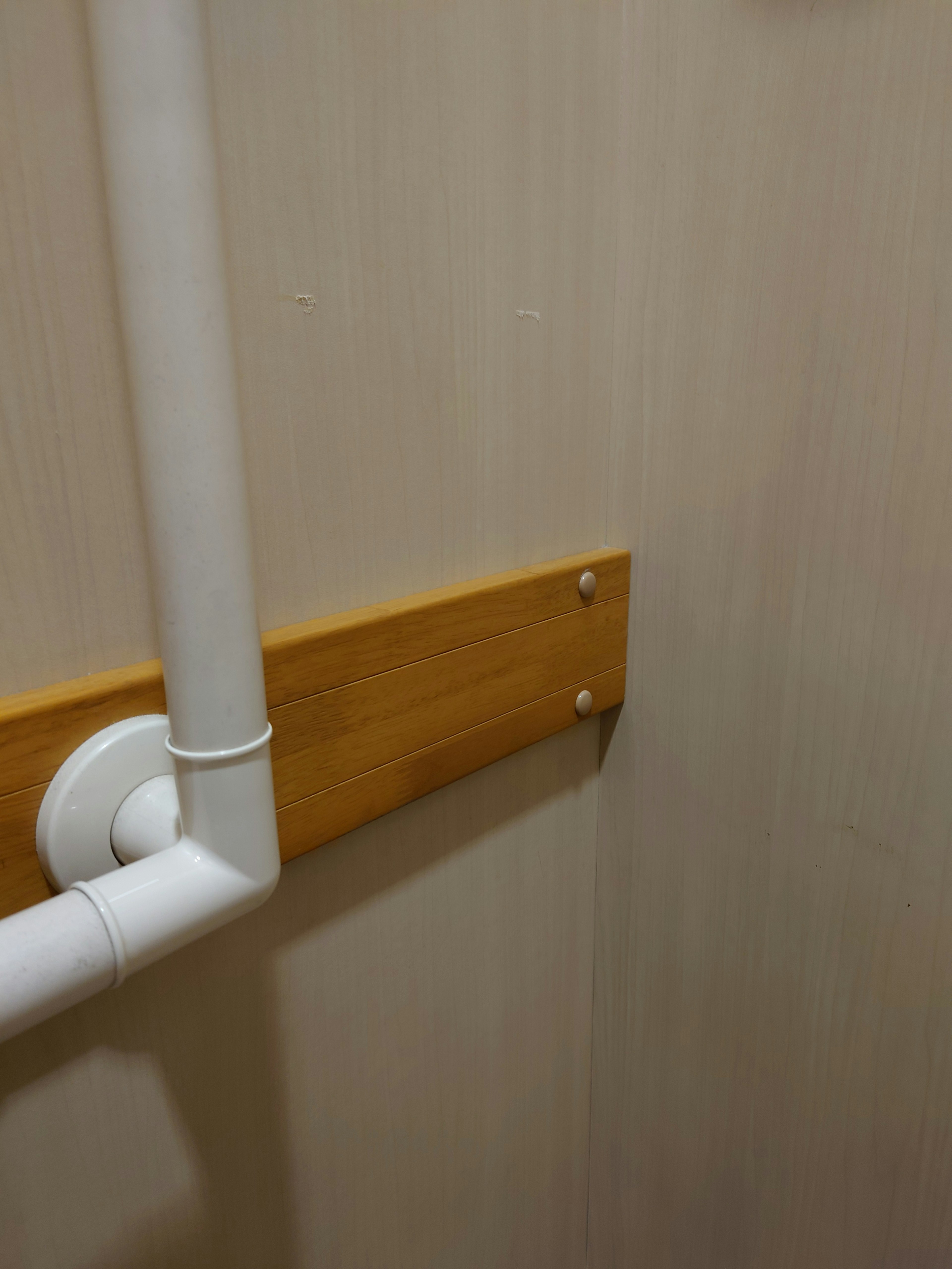 Una sección de pared con un tubo blanco y un panel de madera