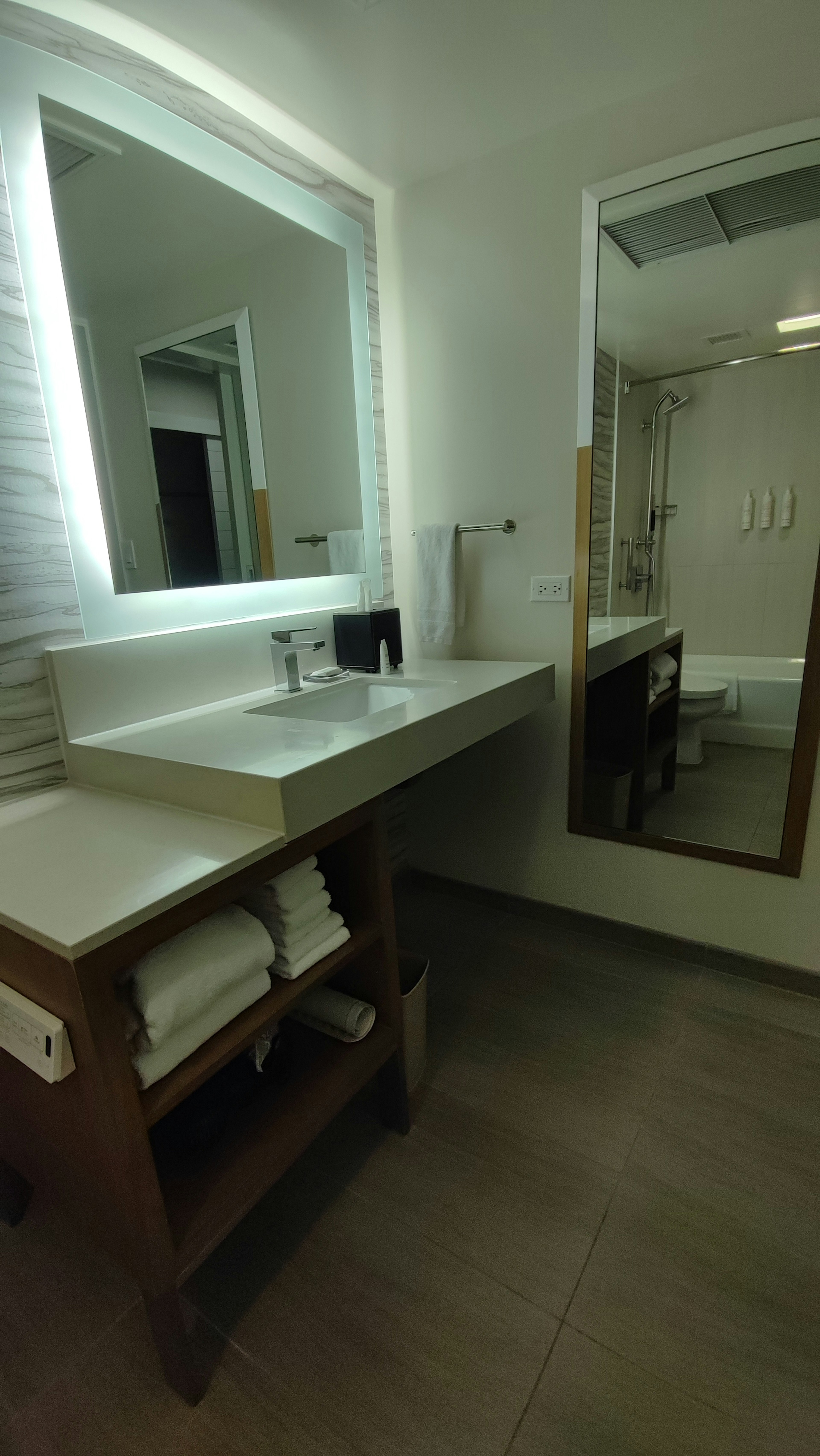 Bright bathroom with a sink and large mirror Neatly arranged towels on a wooden shelf