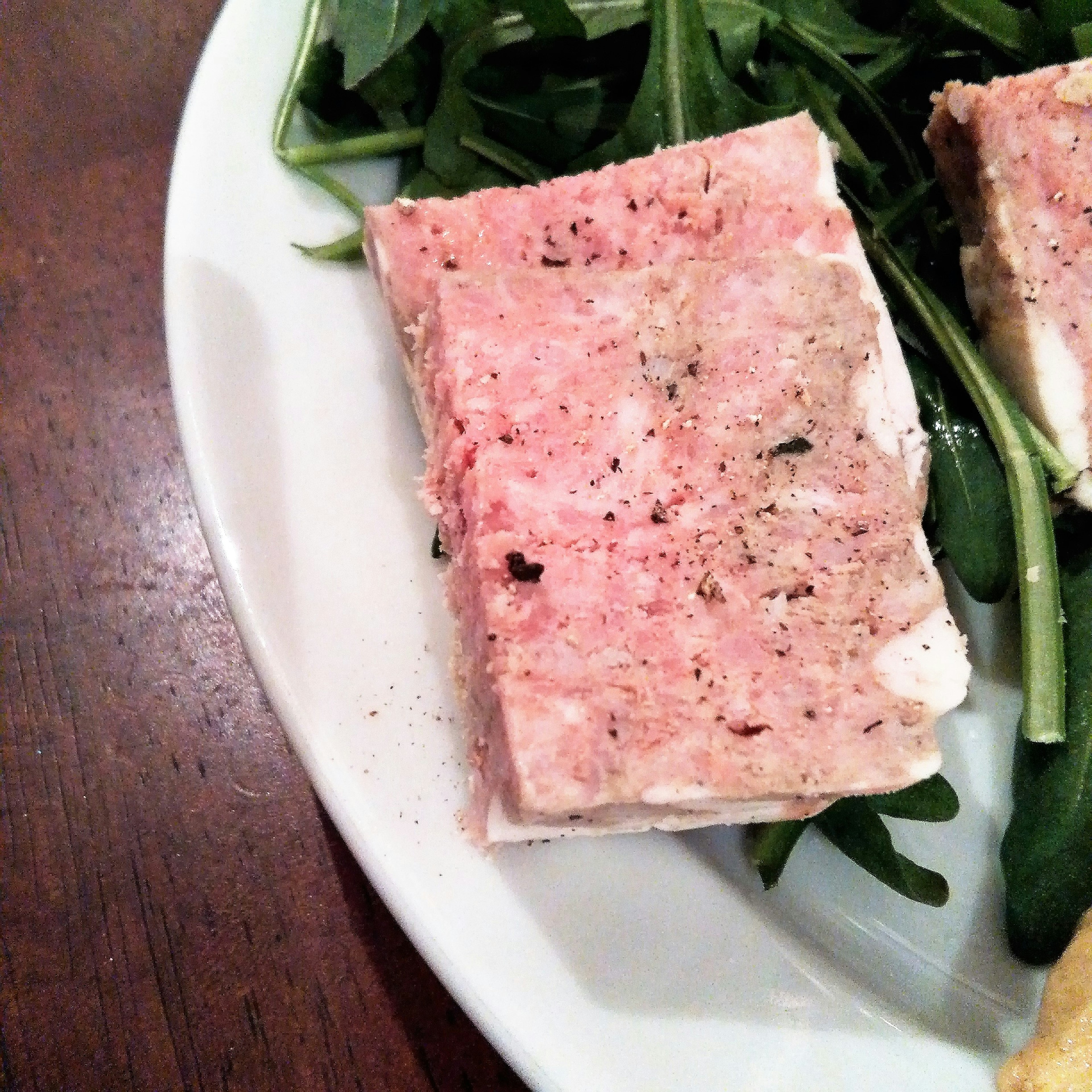 Slice of pâté served on a plate with arugula leaves