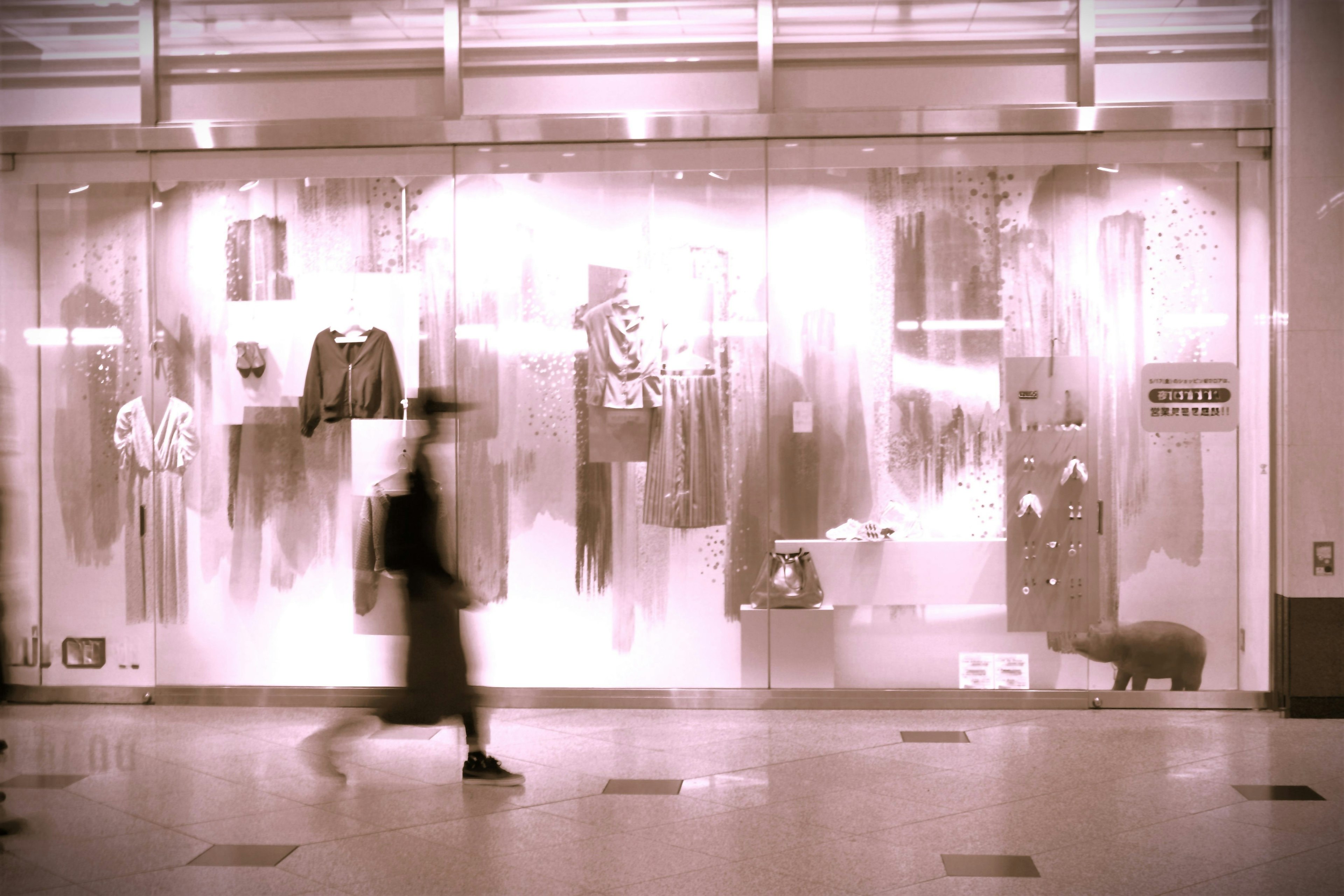 A person walking past a fashion window display with various clothing items