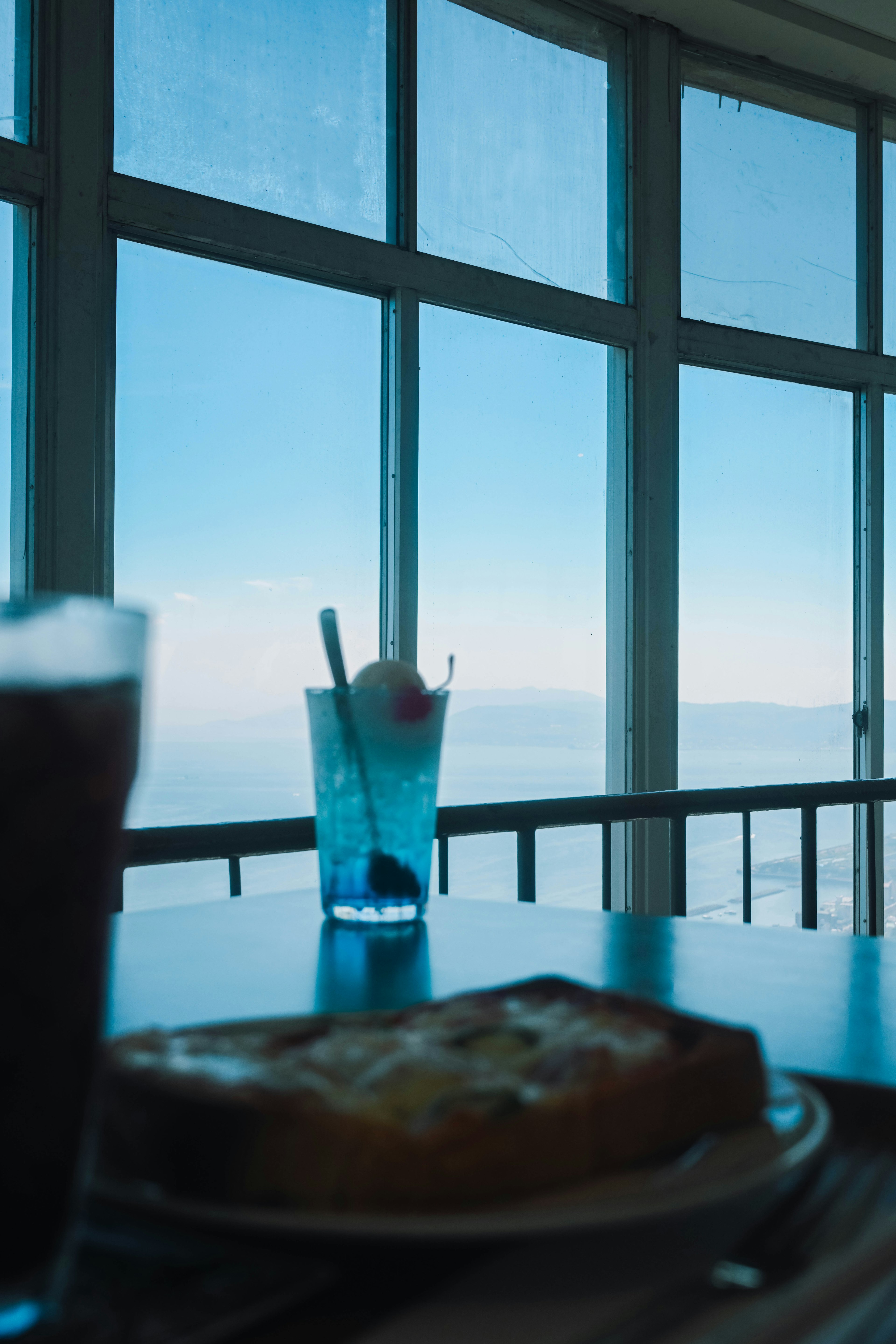 Table avec de la nourriture et des boissons devant un ciel bleu magnifique à travers des fenêtres