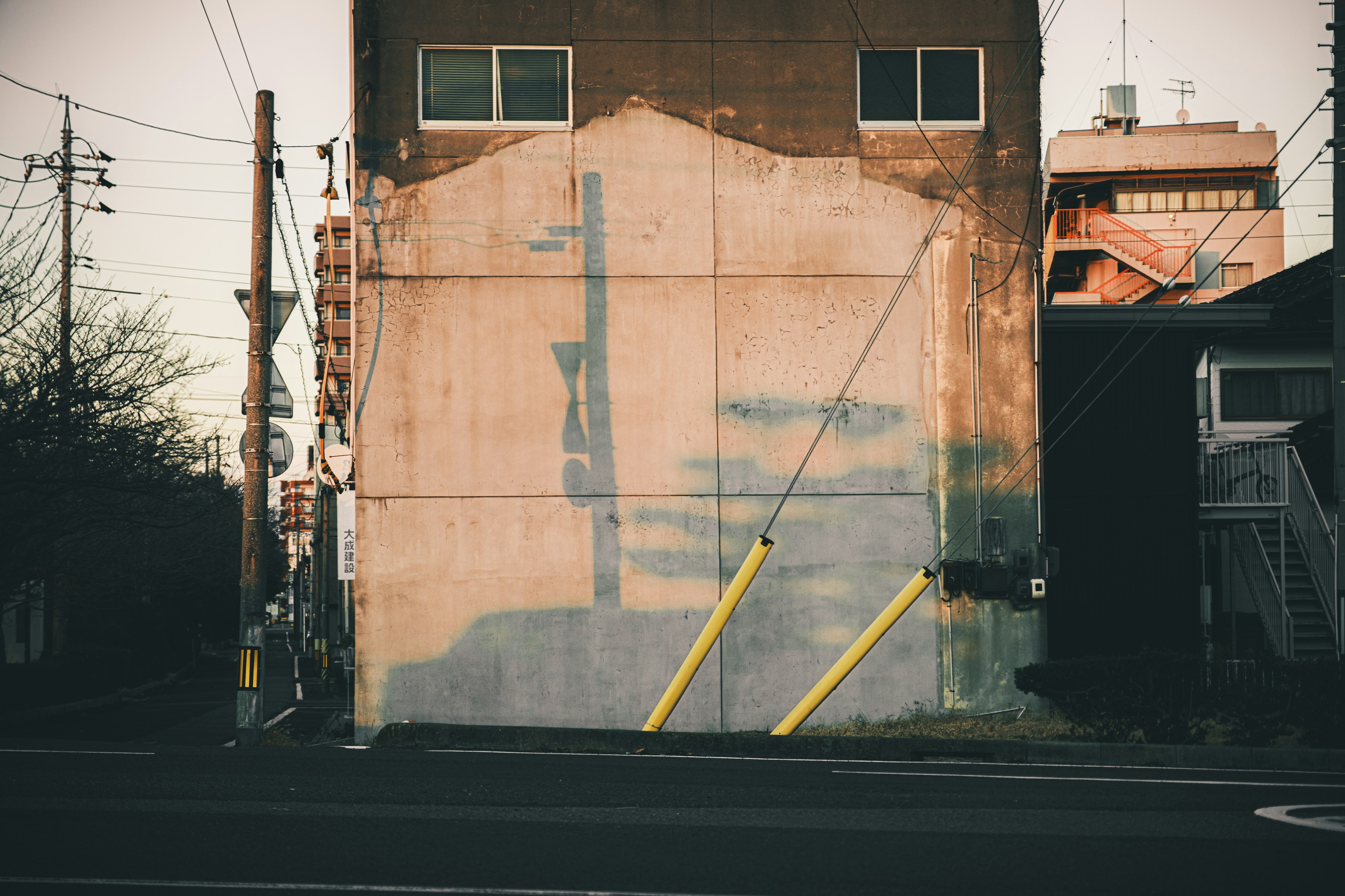 Schatten an einer alten Gebäudewand mit gelben Pfosten