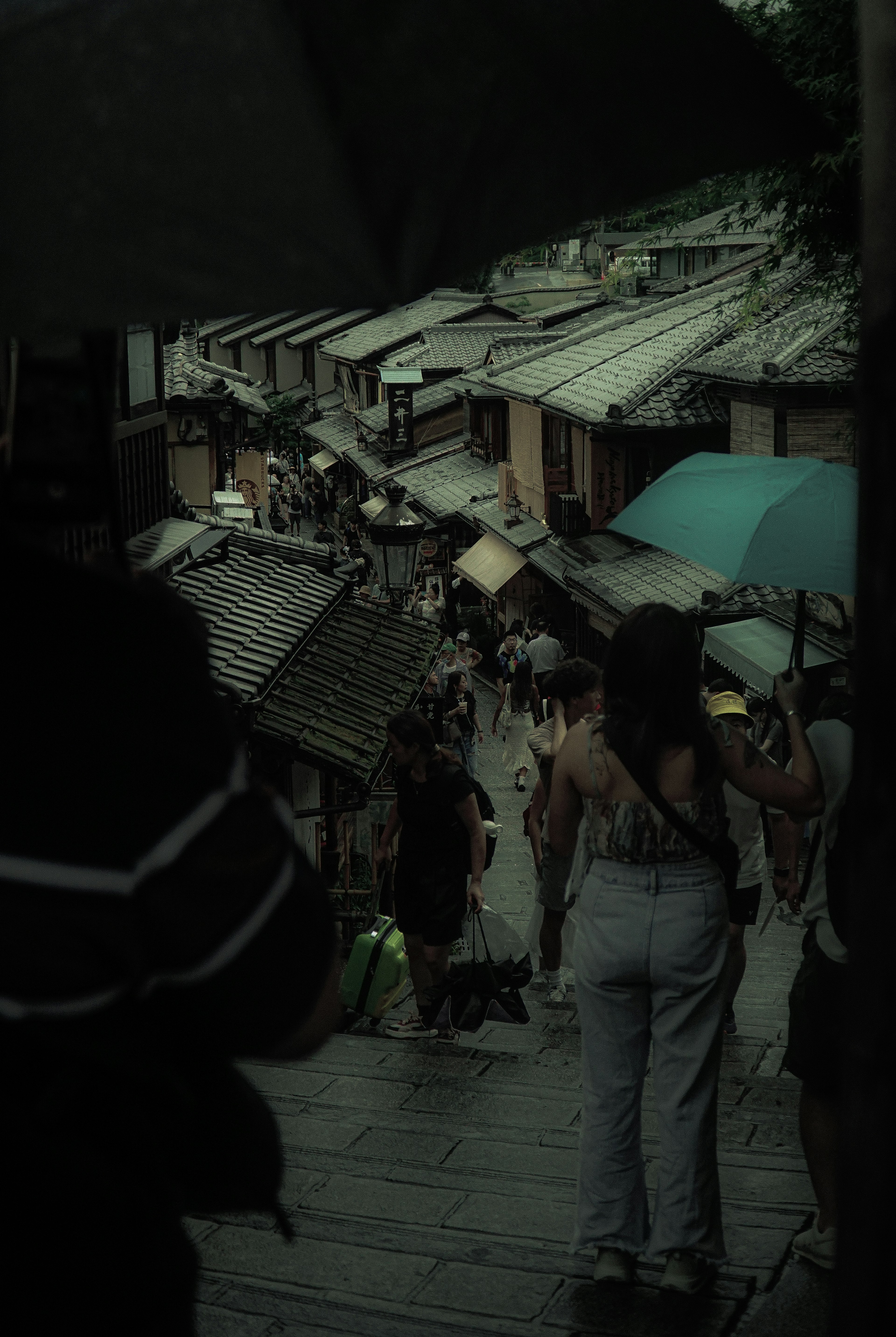 Personas con paraguas caminando por una calle de un pueblo antiguo