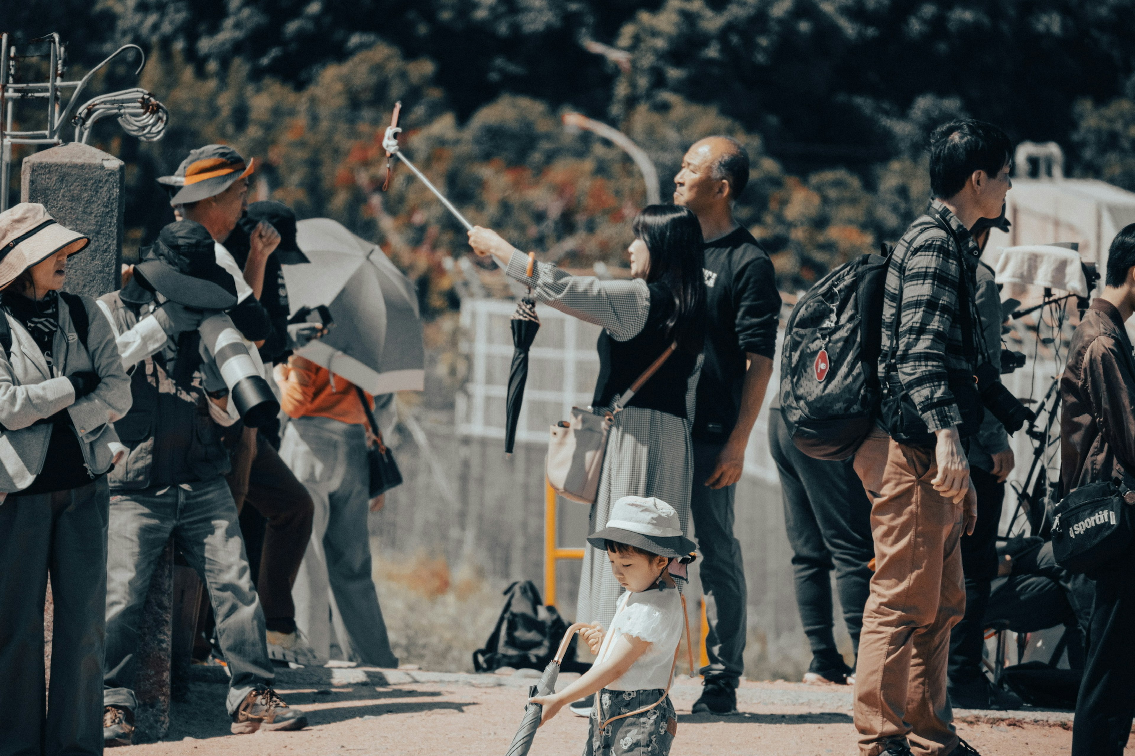 Sebuah adegan dengan kerumunan orang yang memegang kamera dan seorang anak di latar depan