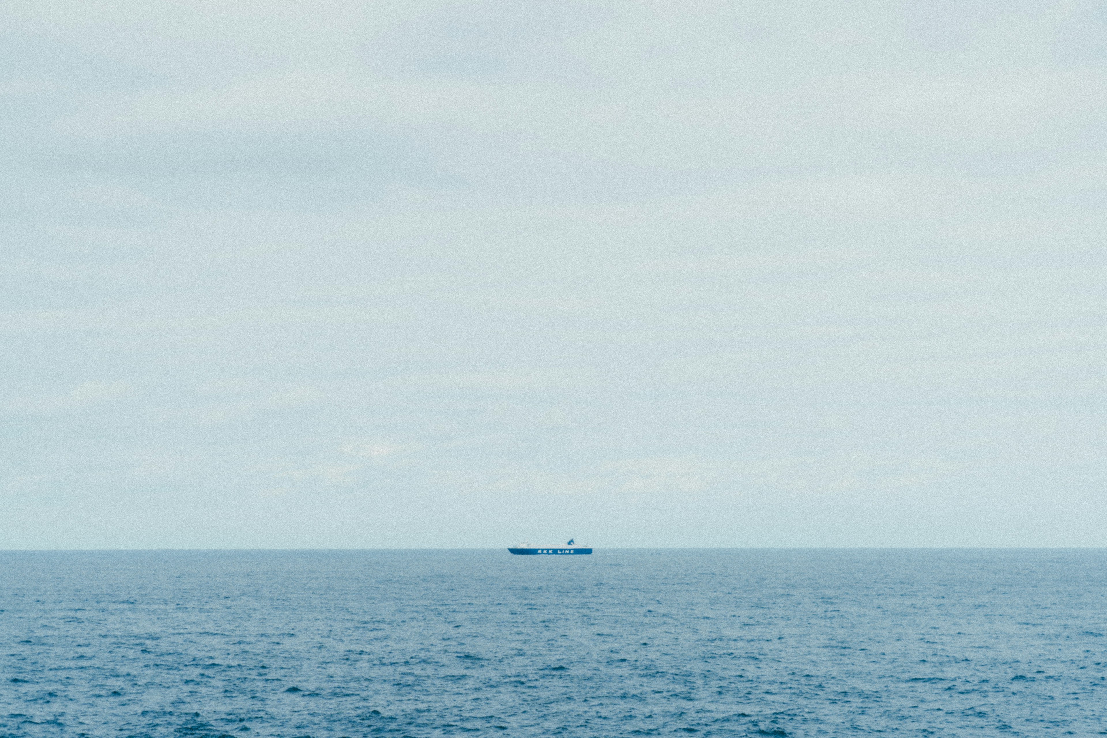 静かな海の上に浮かぶ船と曇り空