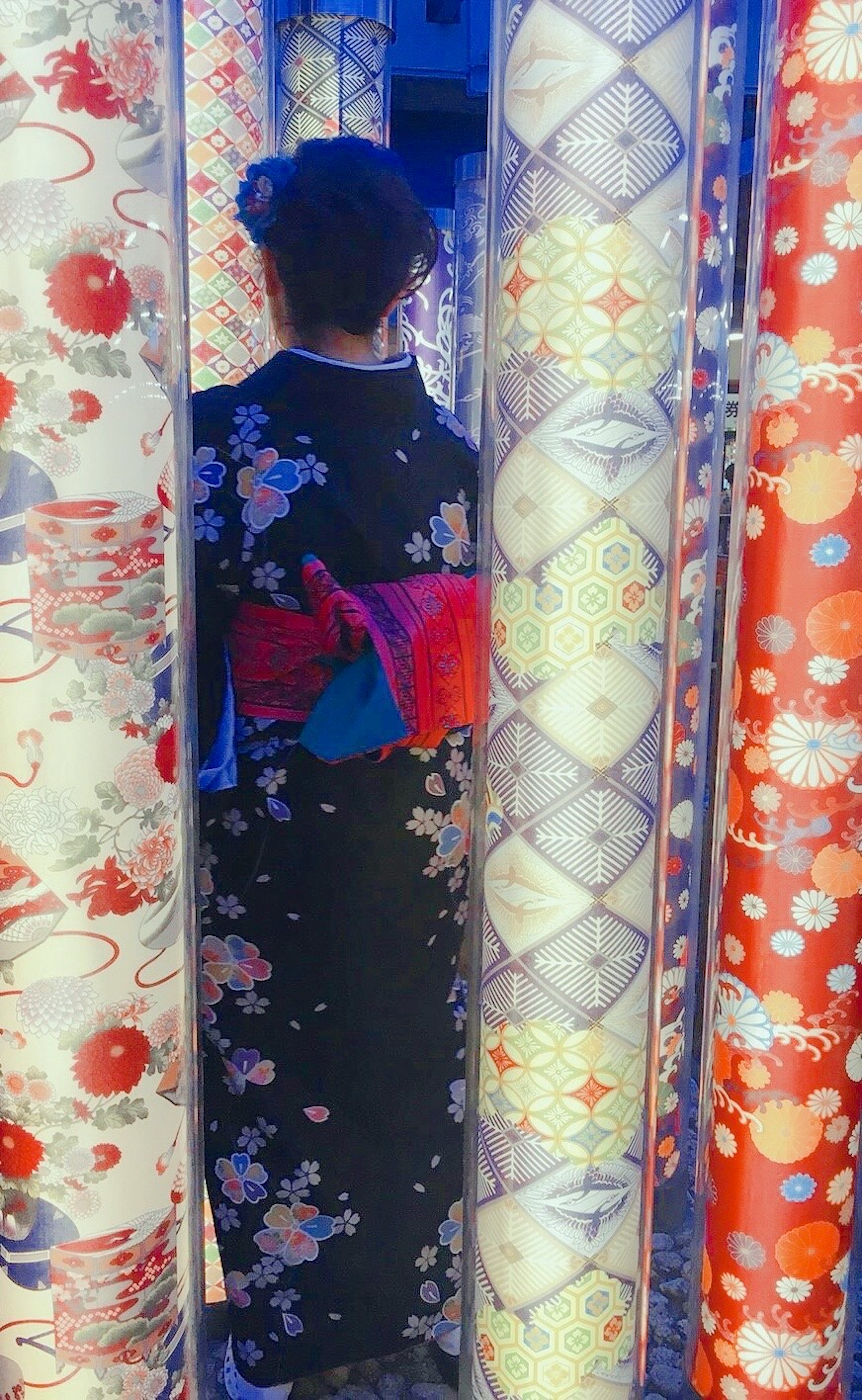 A woman in a colorful kimono standing between traditional fabric columns