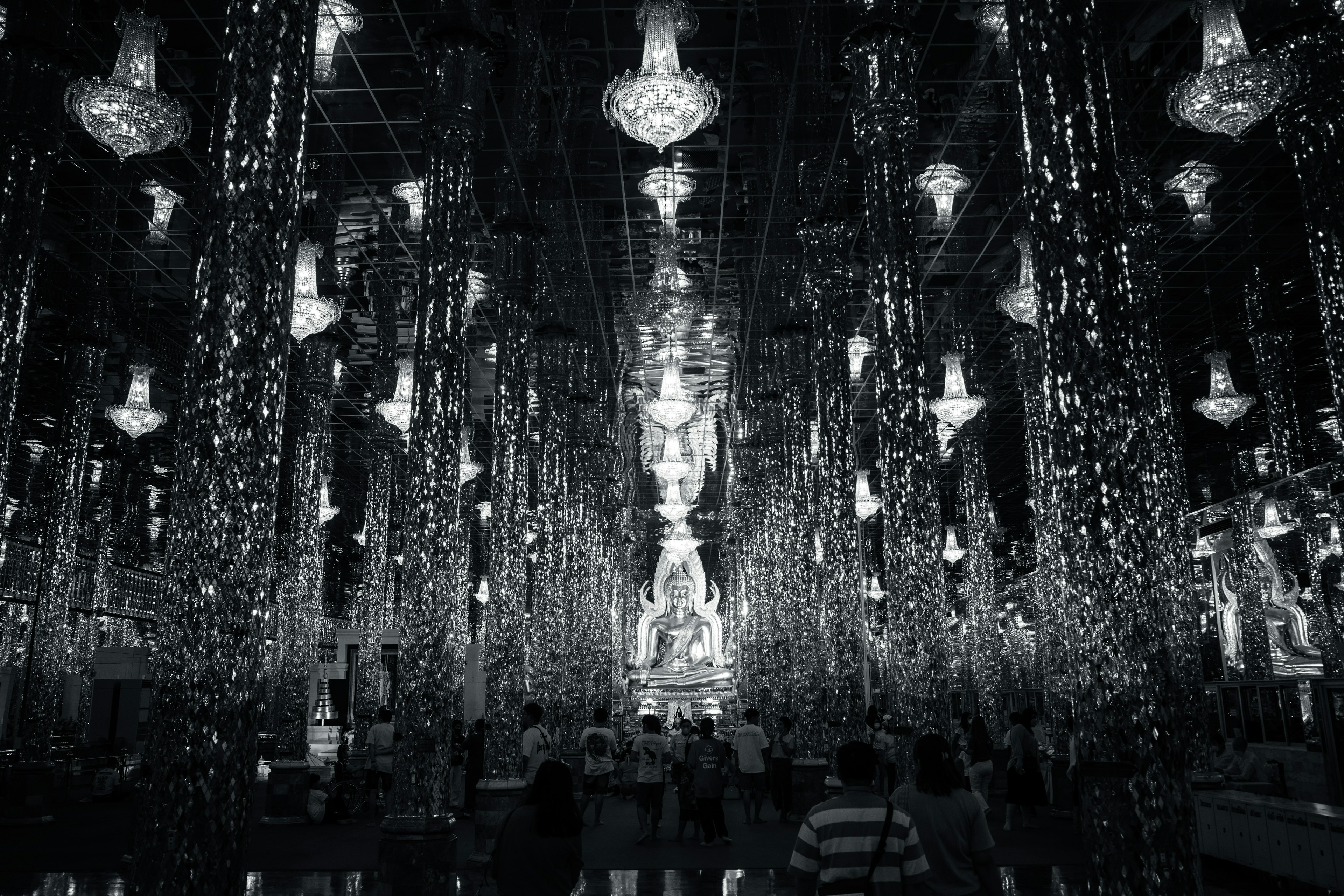 A vast space filled with beautiful chandeliers and people gathered around