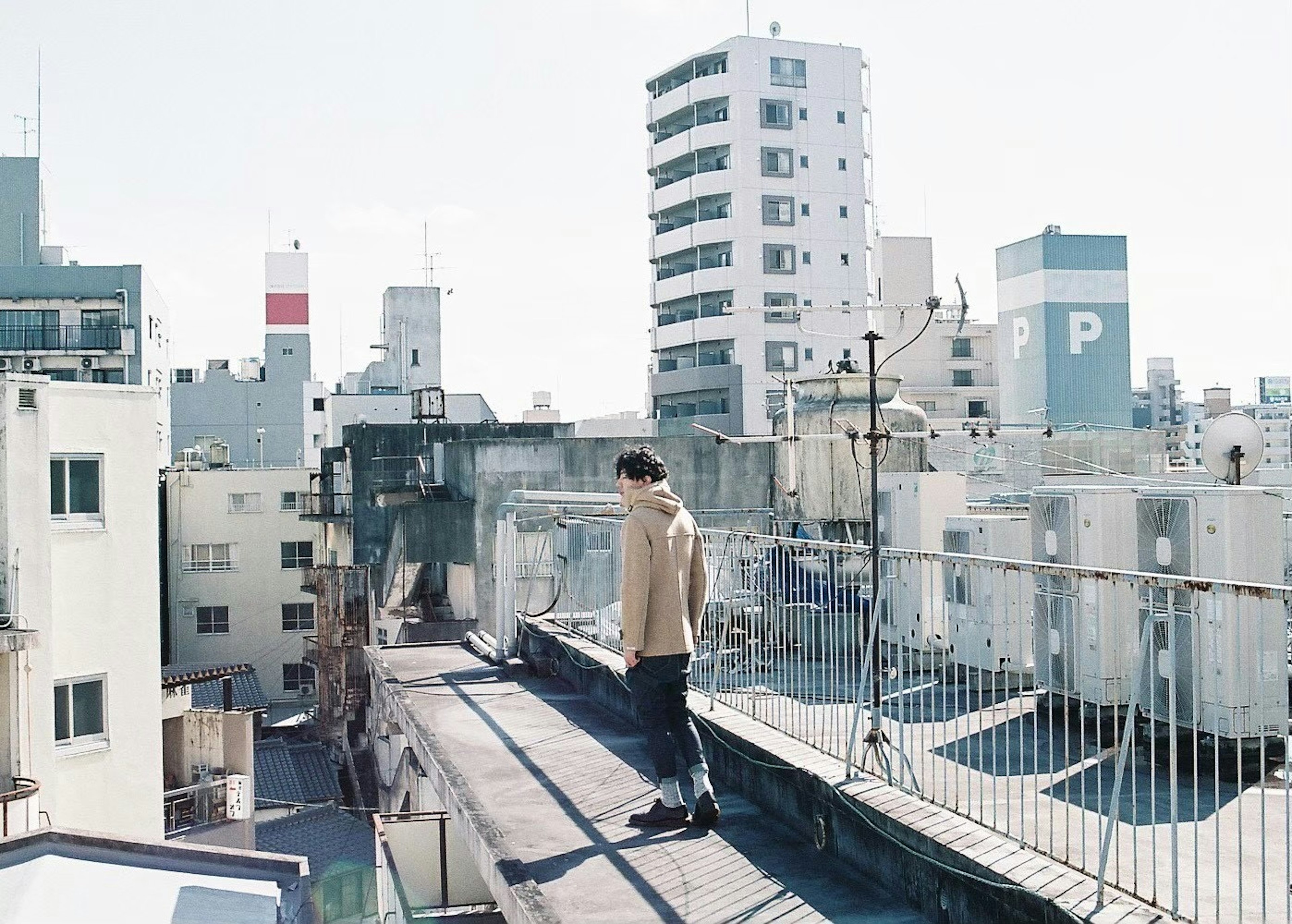 Man standing on rooftop with urban skyline