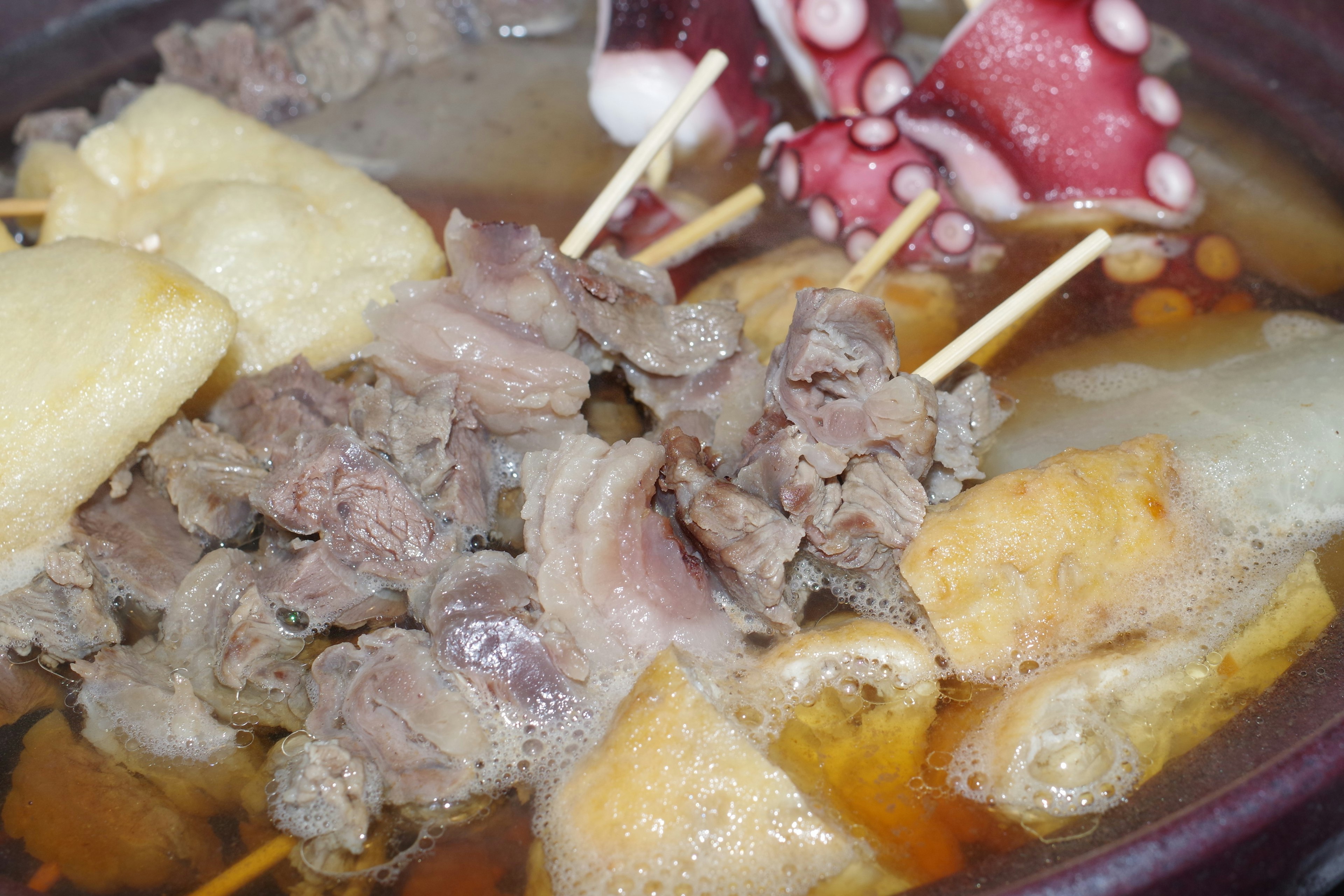 Viande et poulpe en brochettes dans un pot chaud