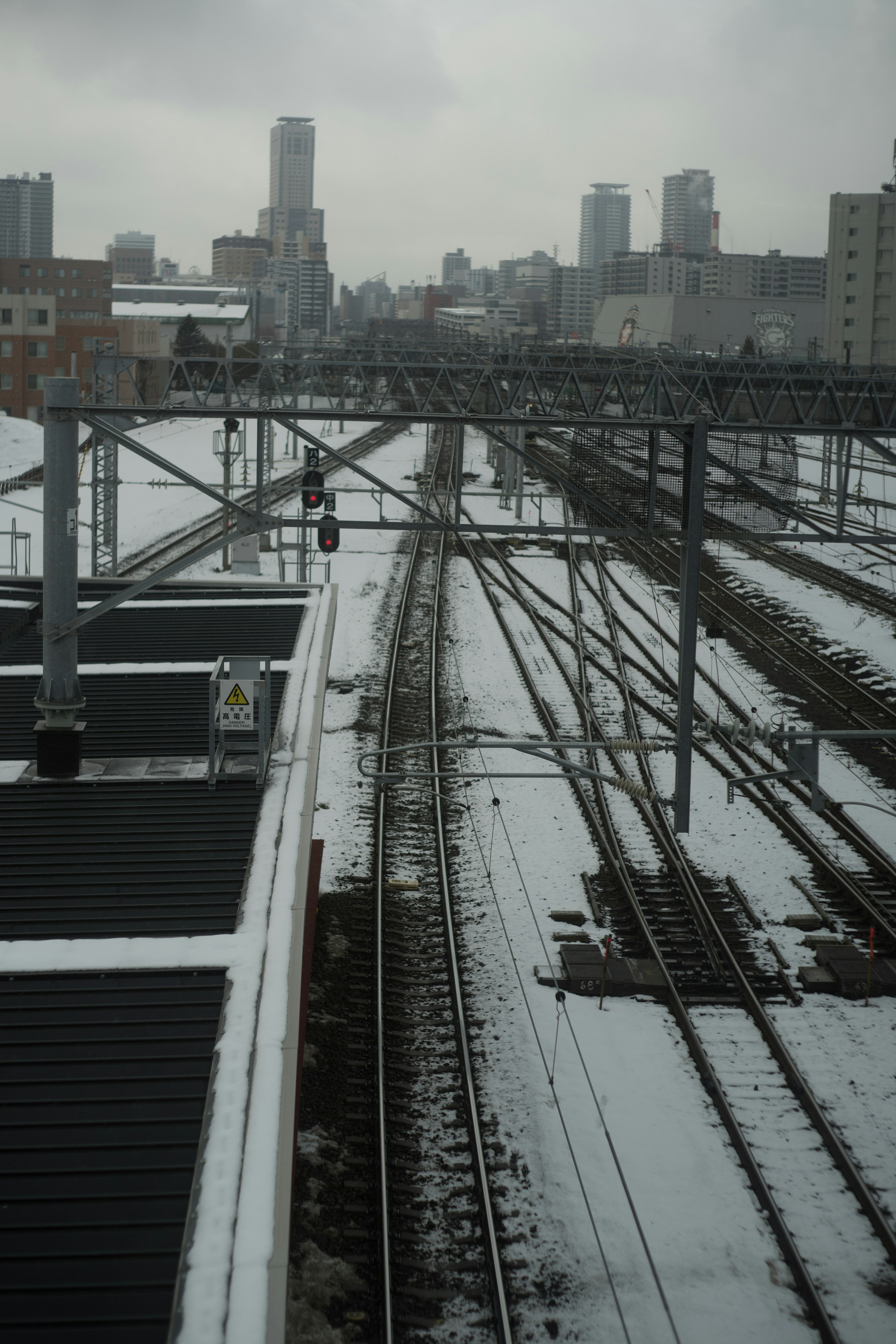 รางรถไฟที่ปกคลุมด้วยหิมะและเส้นขอบฟ้าของเมือง