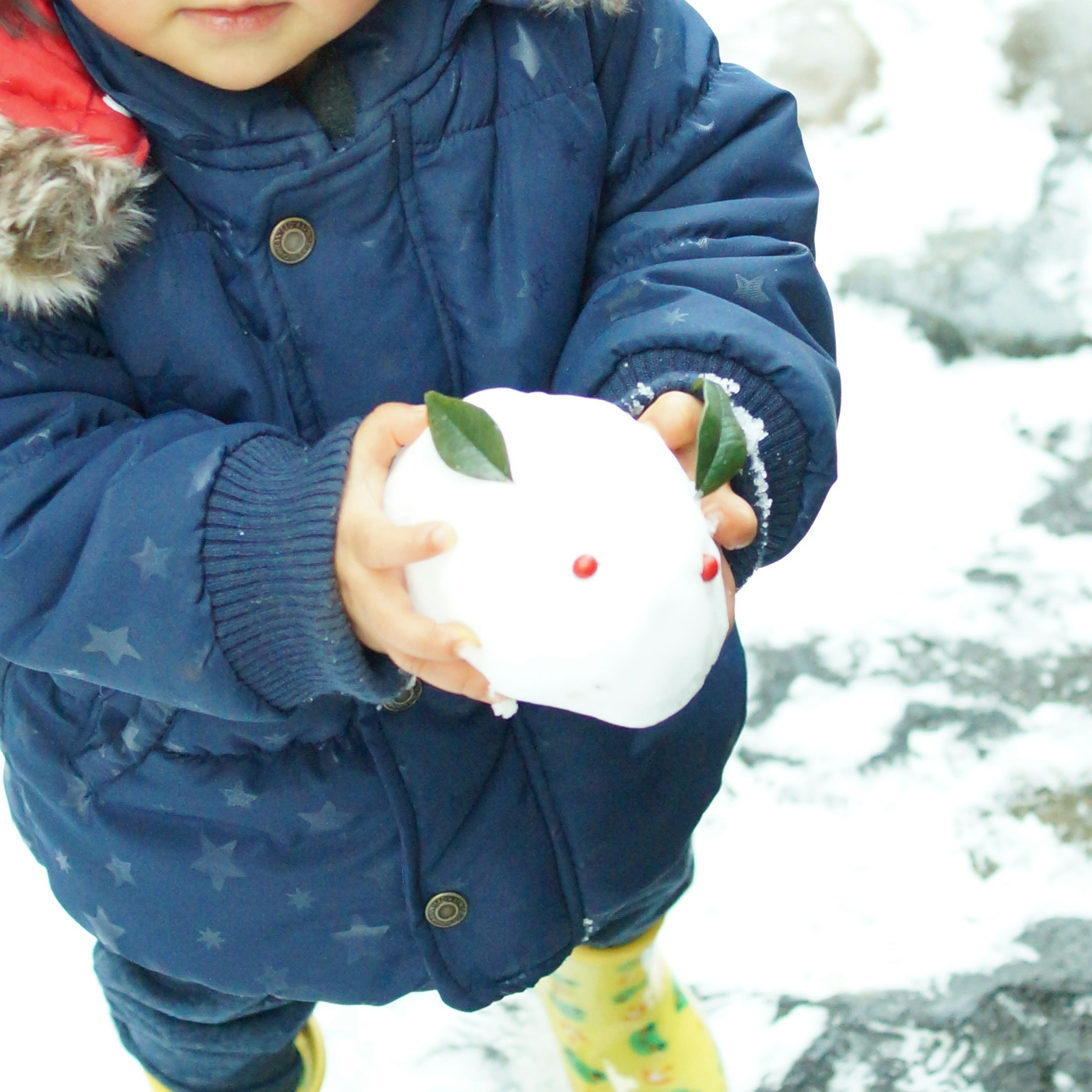 Kind hält einen Schneemann im Schnee