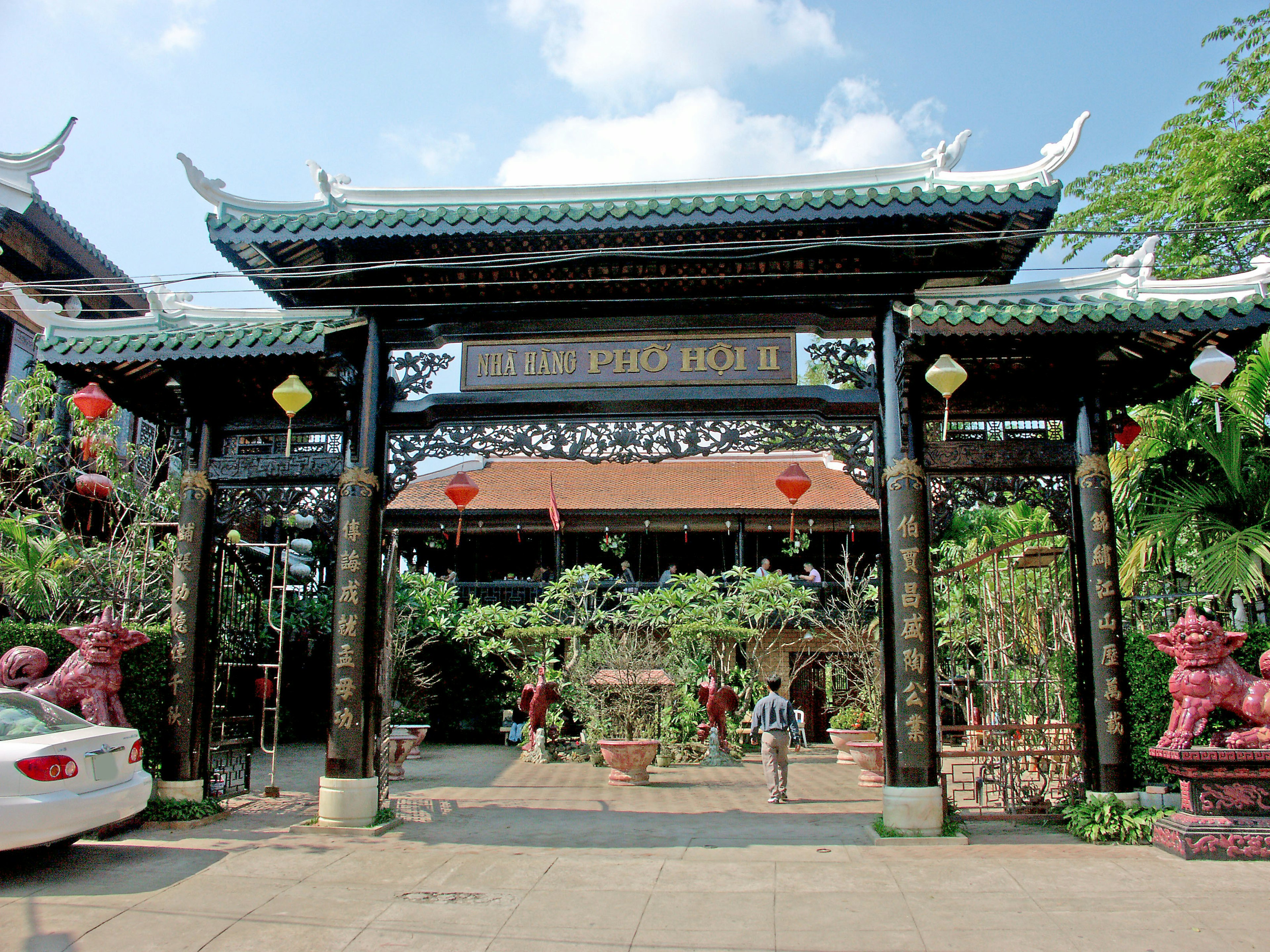 An ornate Asian-style gate with lush greenery and red lanterns in the garden