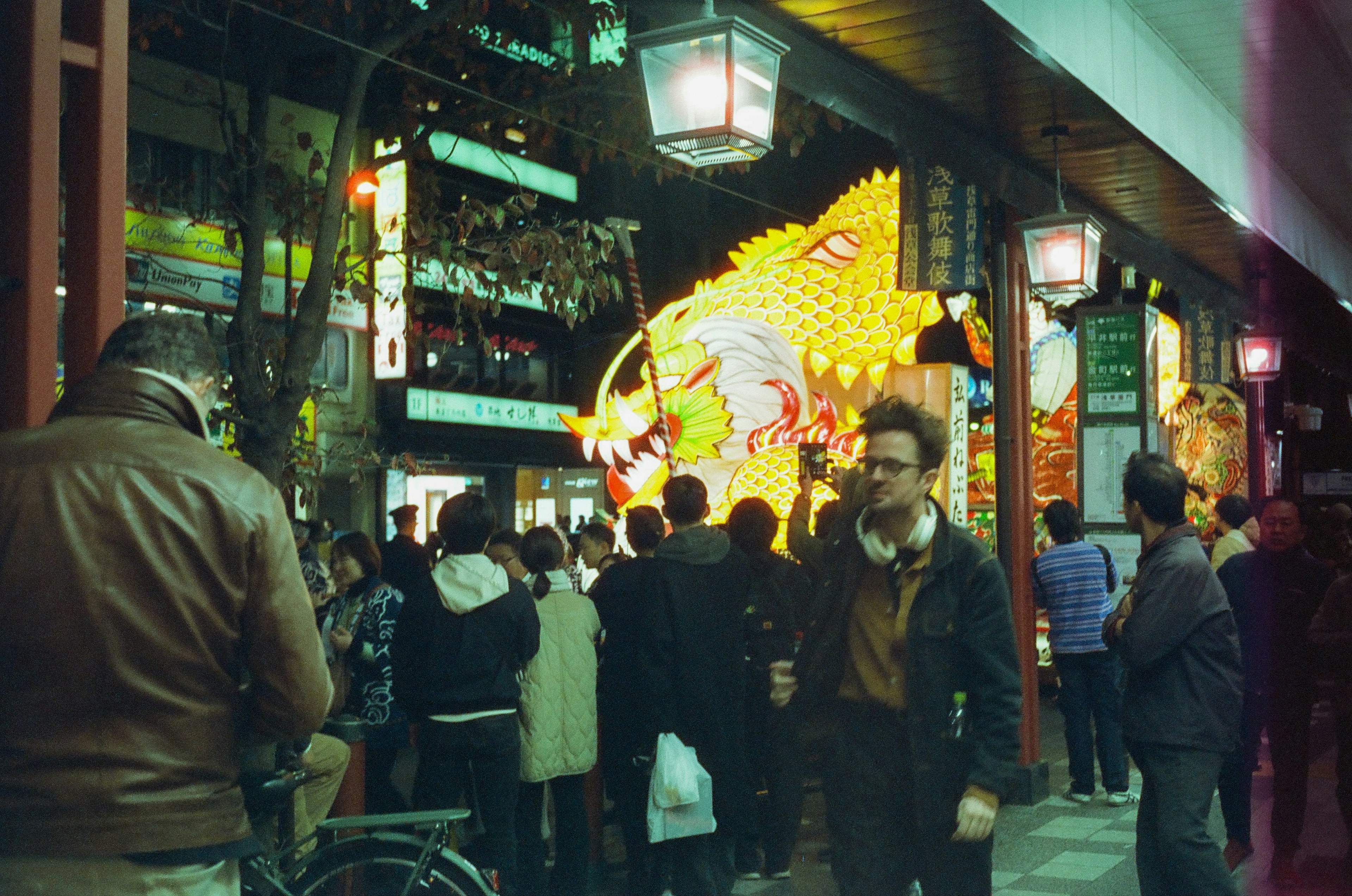 Crowd gathered on a festive street with a large dragon decoration at night