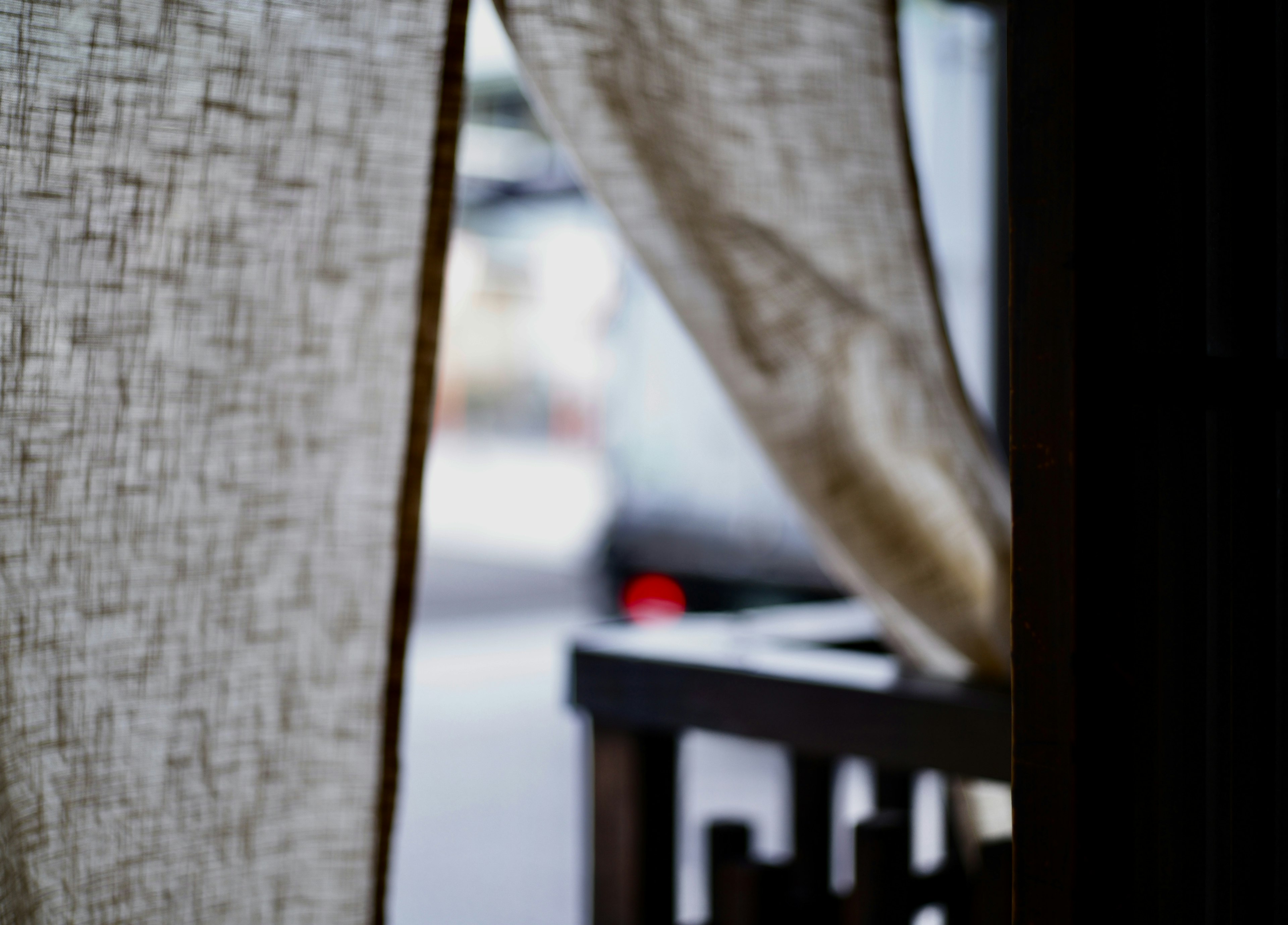 A sheer fabric curtain partially revealing a blurred outdoor scene