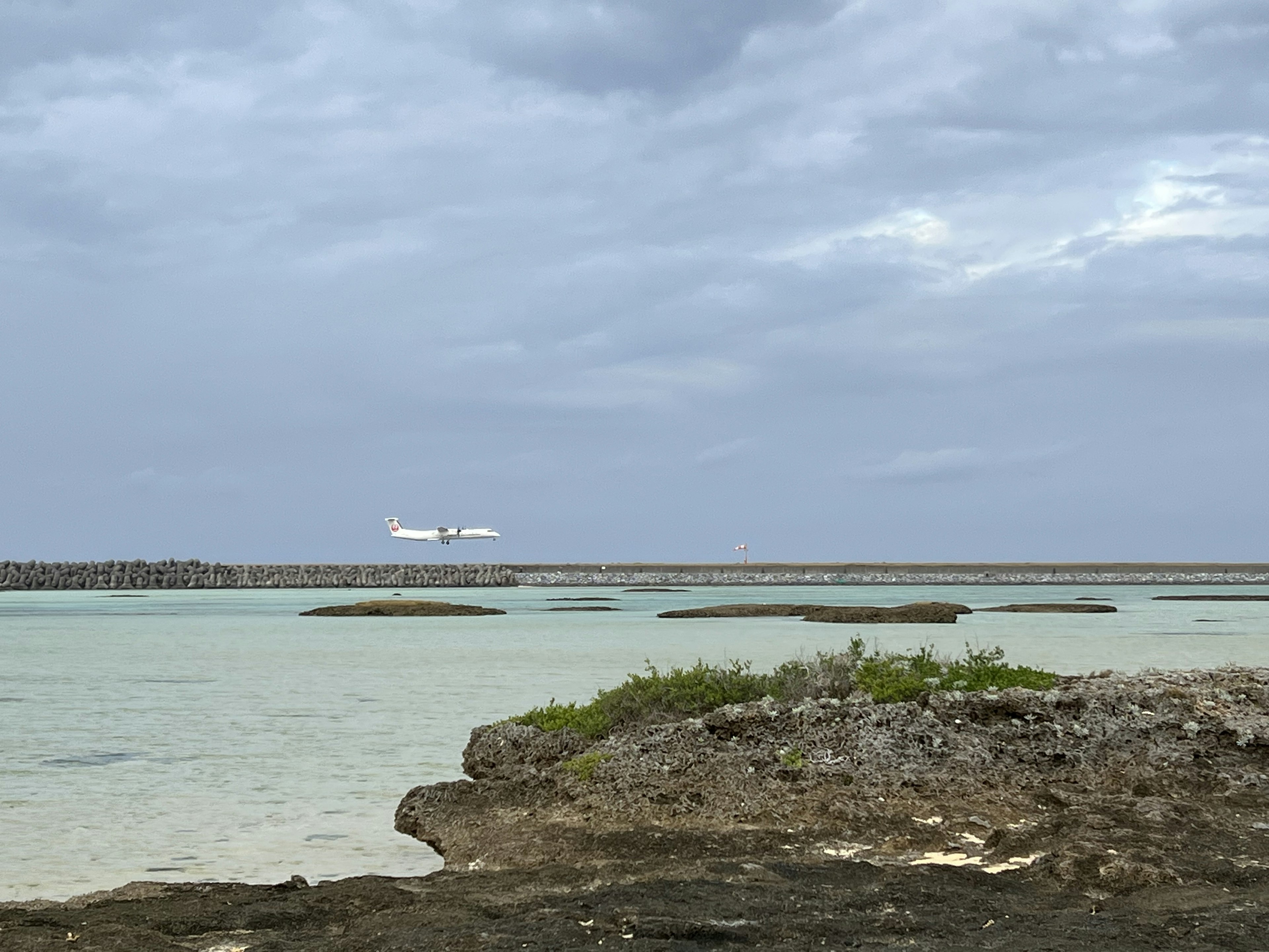 Un avión volando sobre aguas poco profundas cerca de costas rocosas