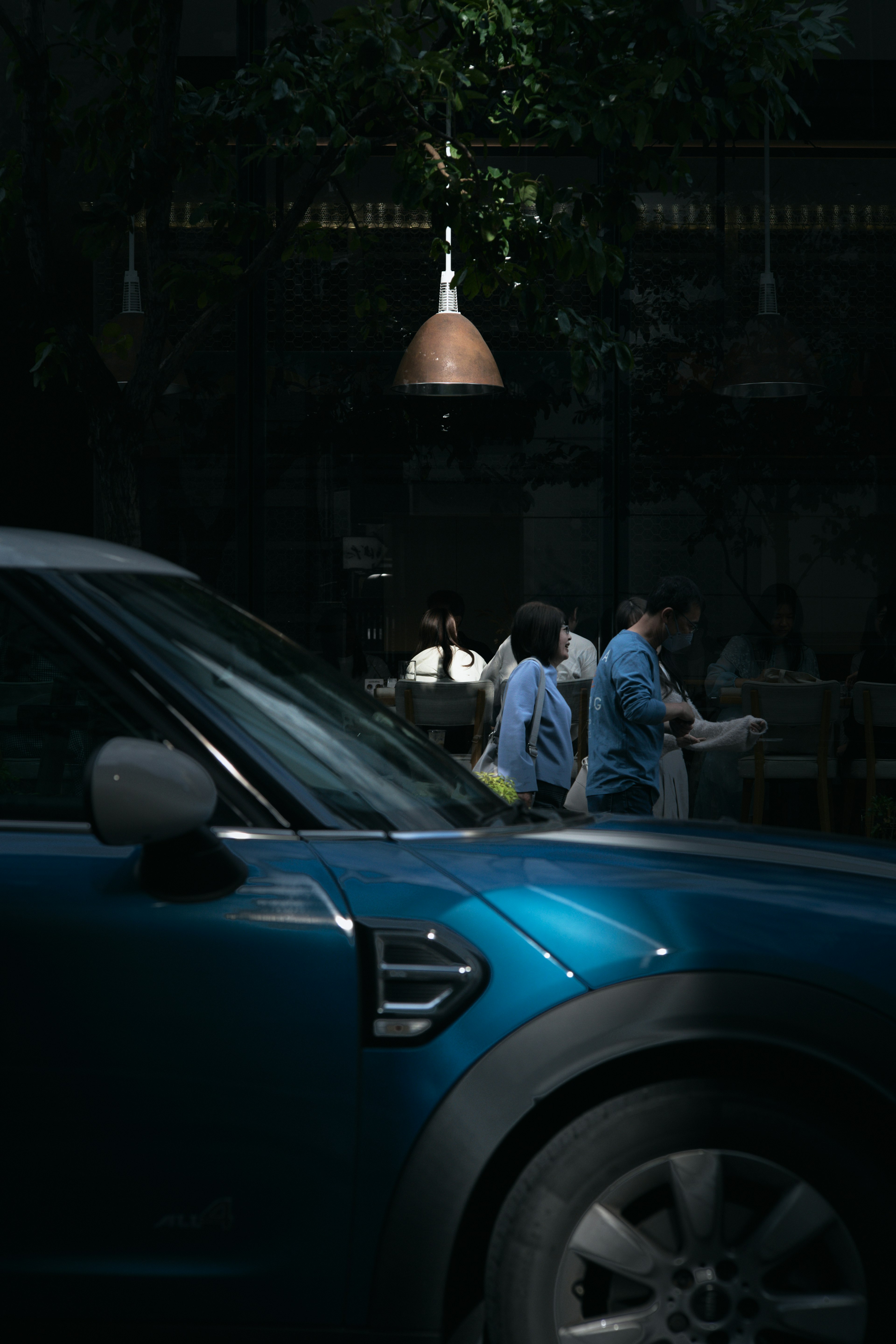 A blue car with pedestrians walking in a city scene