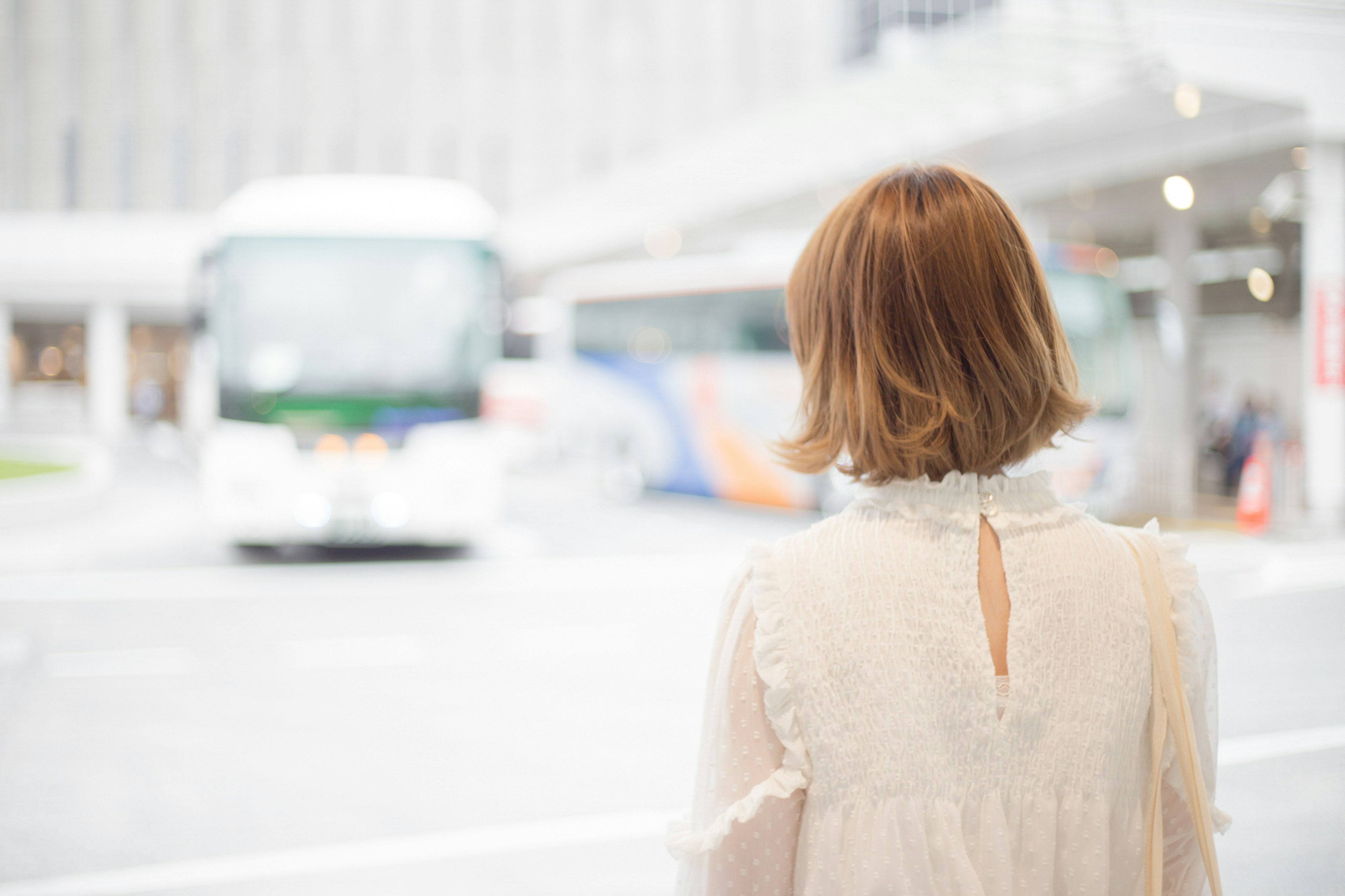 Woman waiting at a bus stop looking at the bus