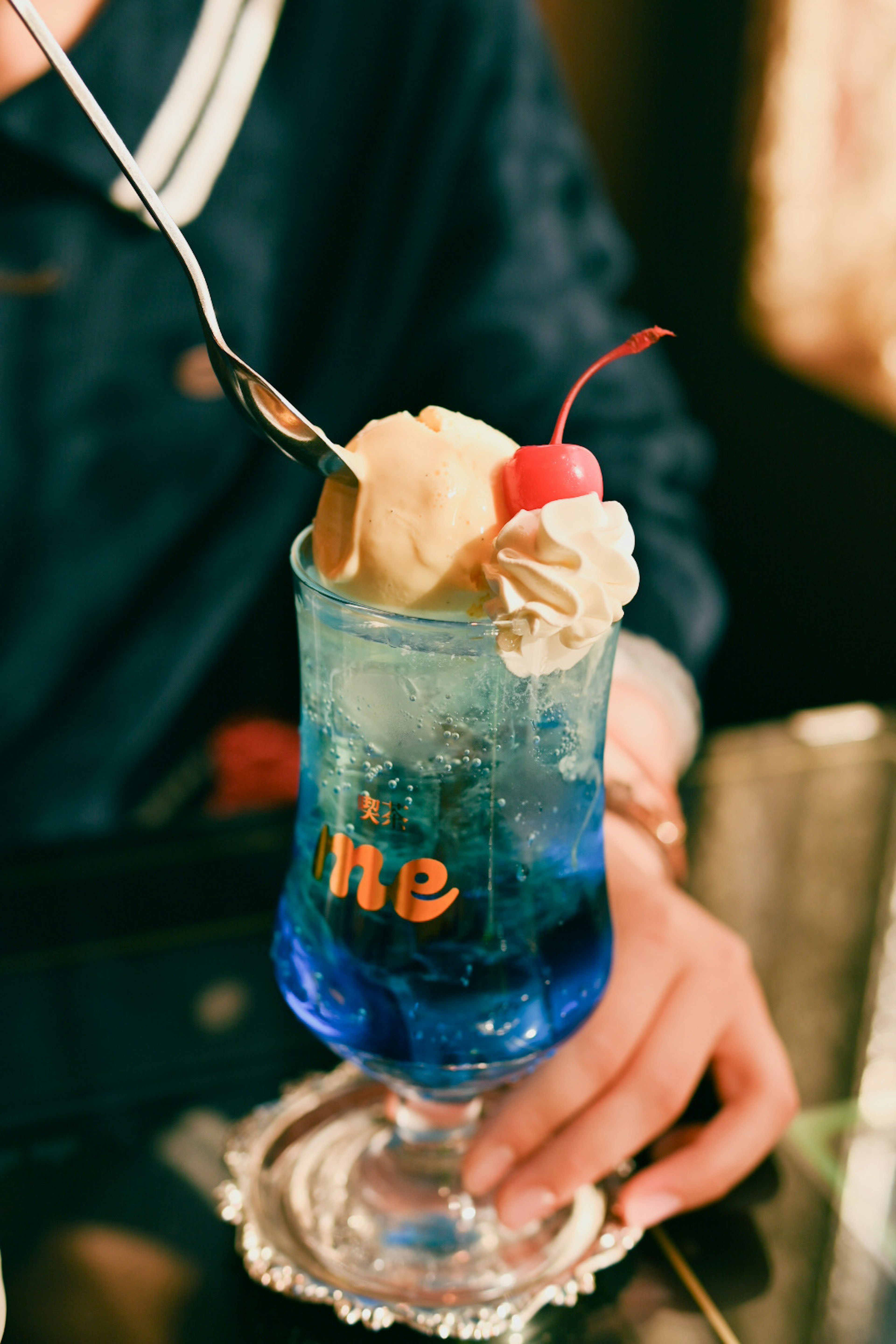 Dessert drink with blue beverage topped with ice cream and cherry