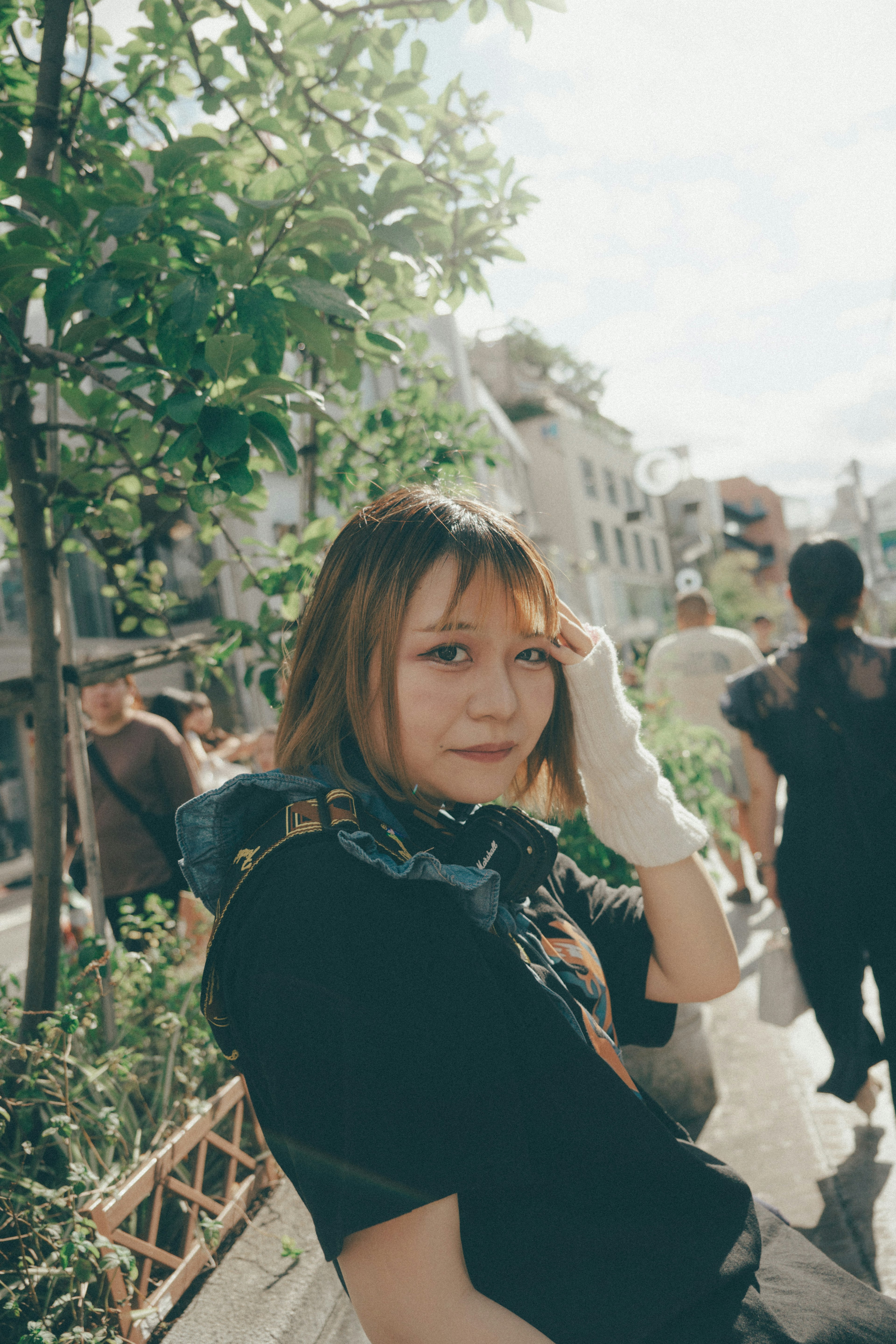 Portrait d'une femme souriante parmi des arbres verts avec des gens en arrière-plan