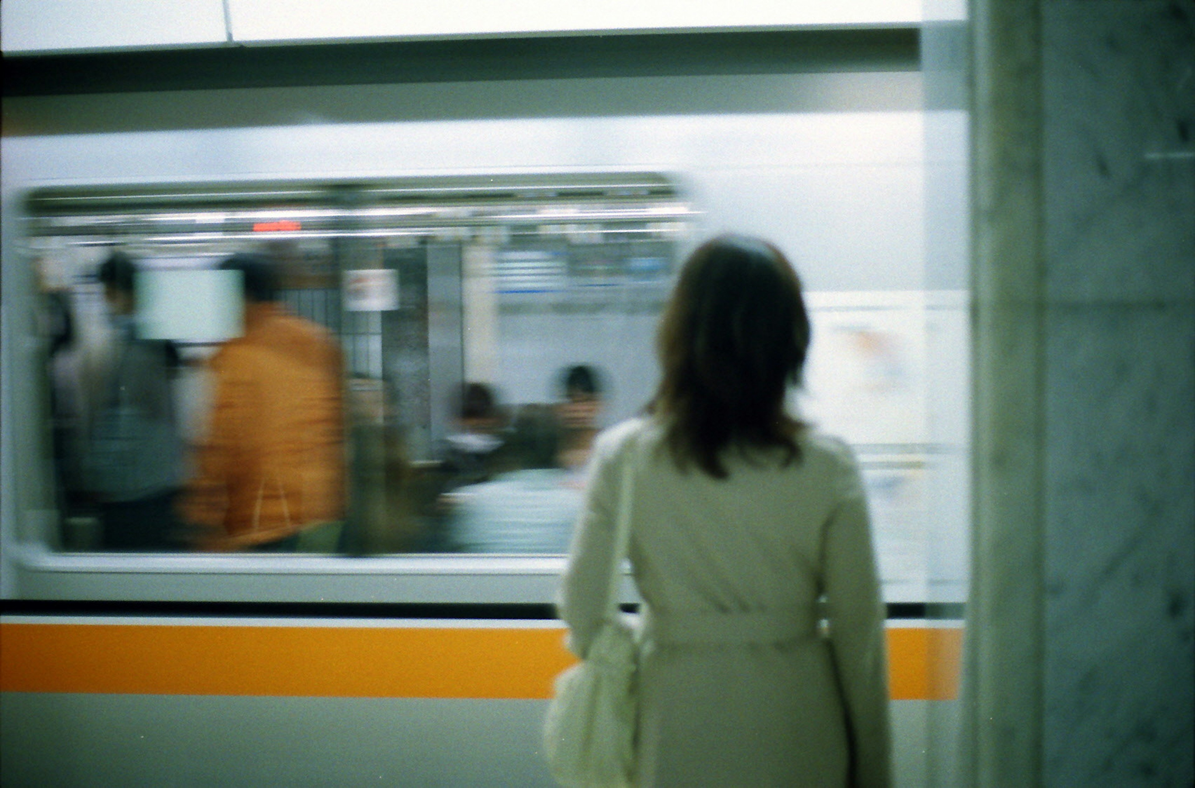 A woman waiting for the subway with a moving train in the background