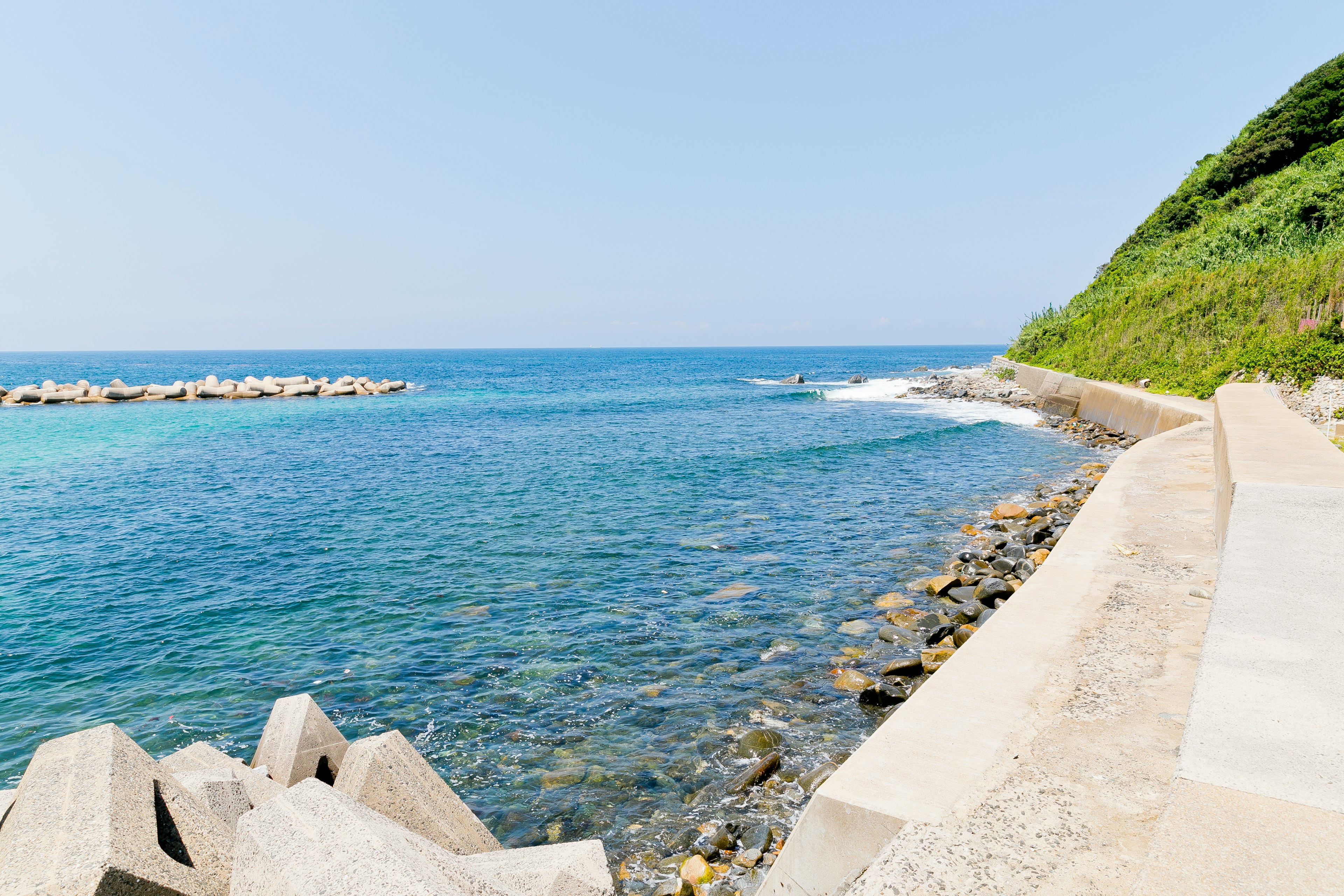 Küstenlandschaft mit blauem Meer und grünem Hügel