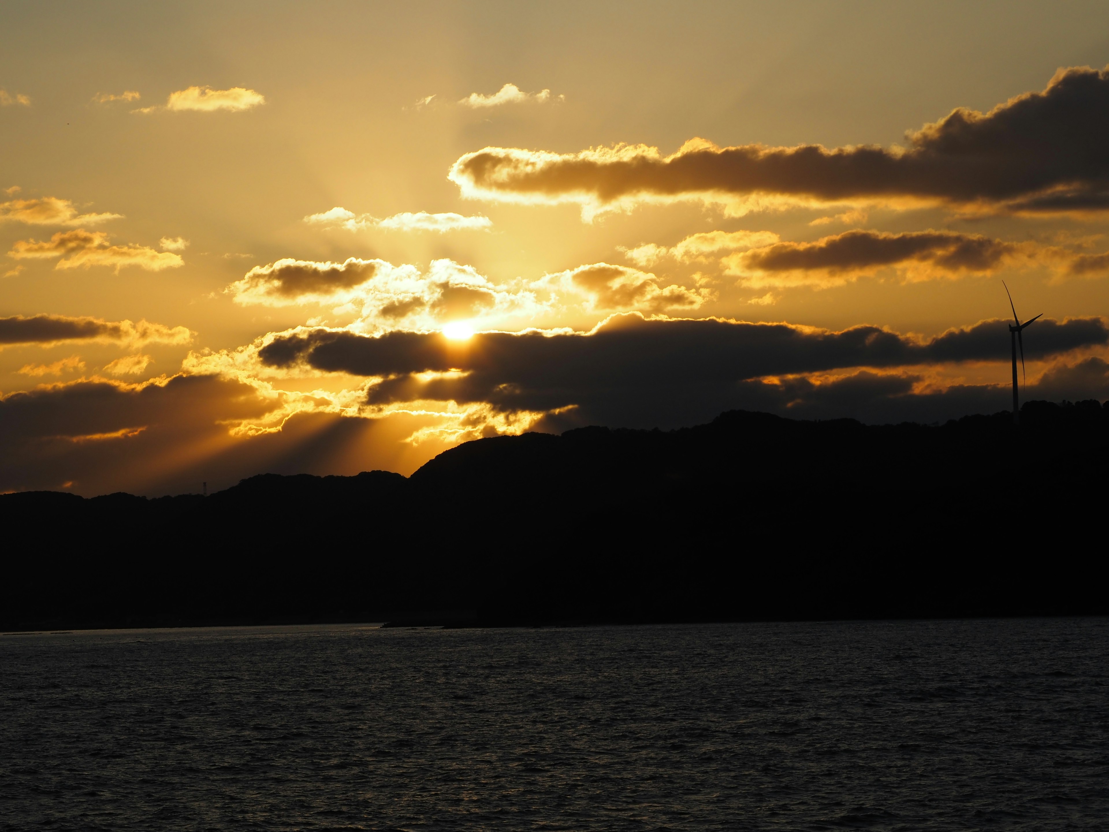 Hermoso atardecer detrás de las montañas con nubes y agua