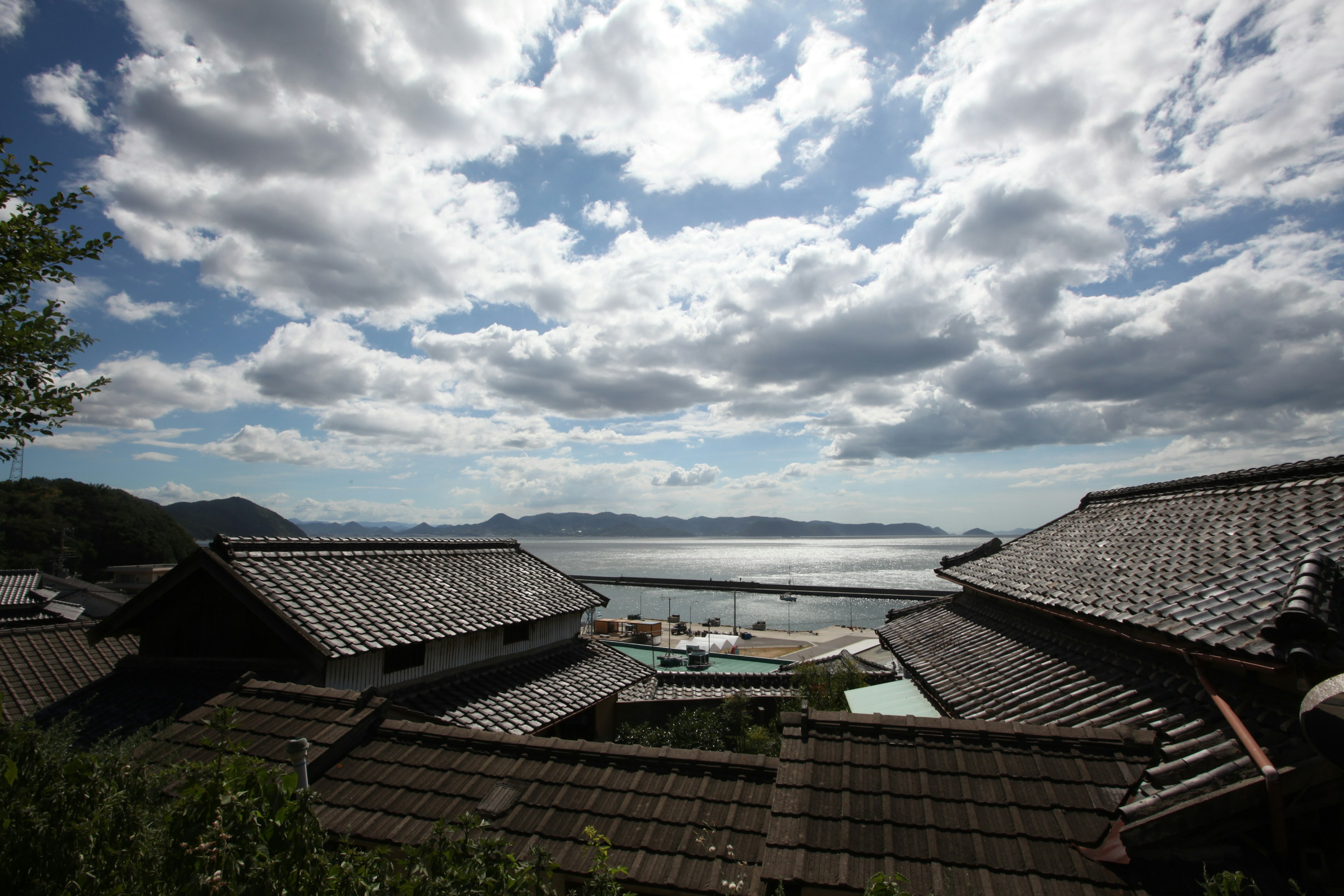 Traditional Japanese rooftops with ocean and cloudy sky