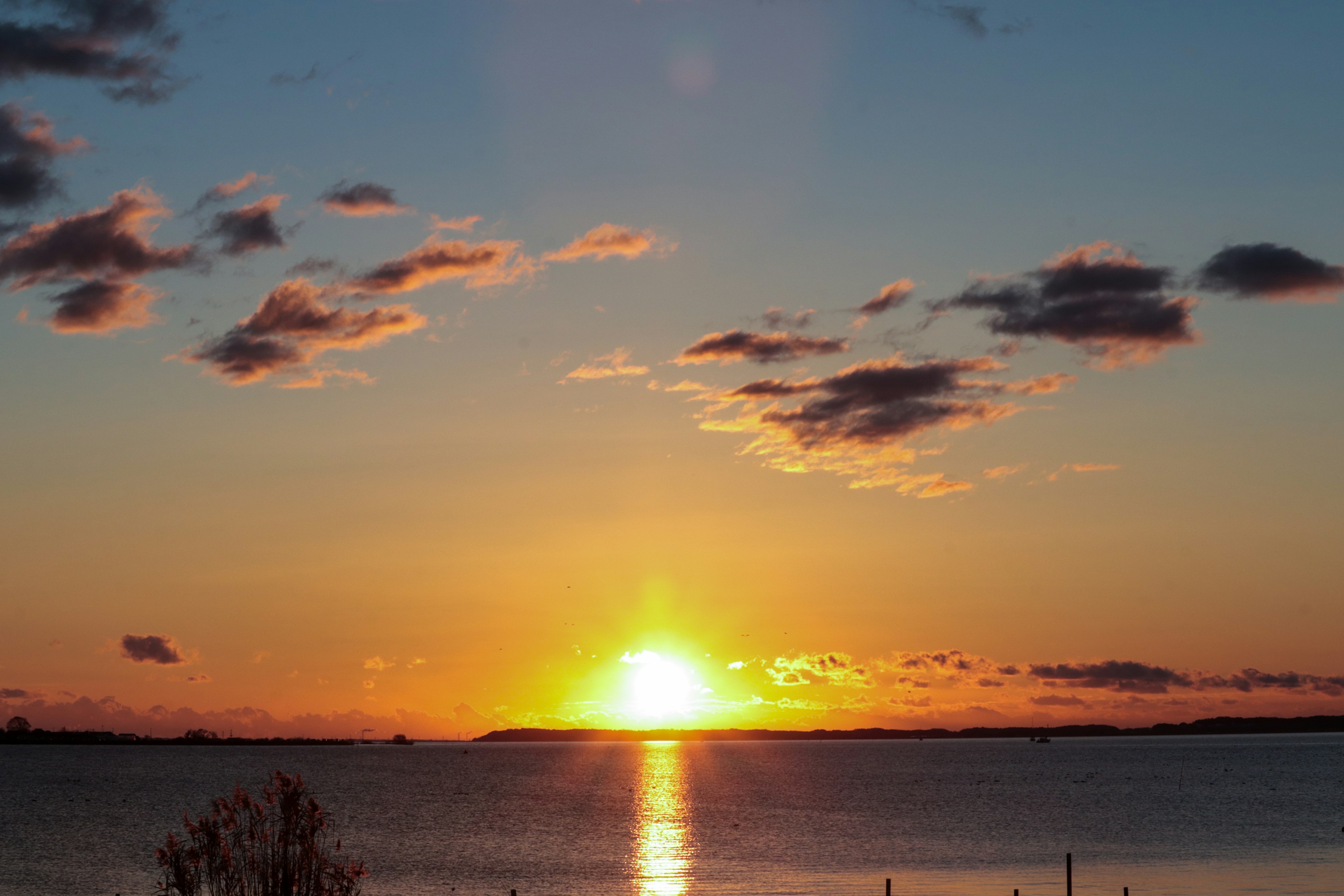 Eine wunderschöne Landschaft des Sonnenuntergangs über dem Meer mit orangefarbenem Himmel und Wolken