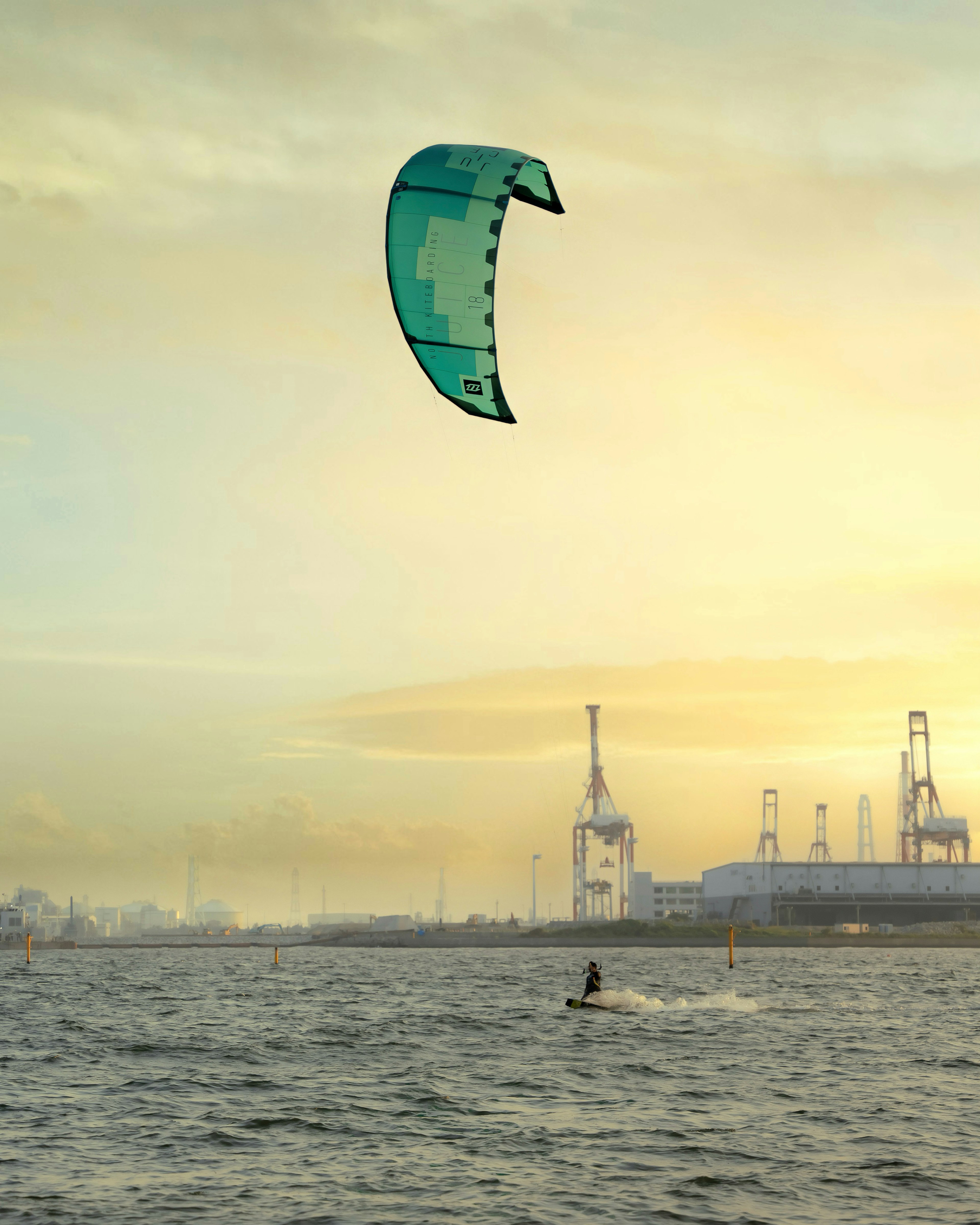 Kitesurfista en el agua con un horizonte industrial al fondo