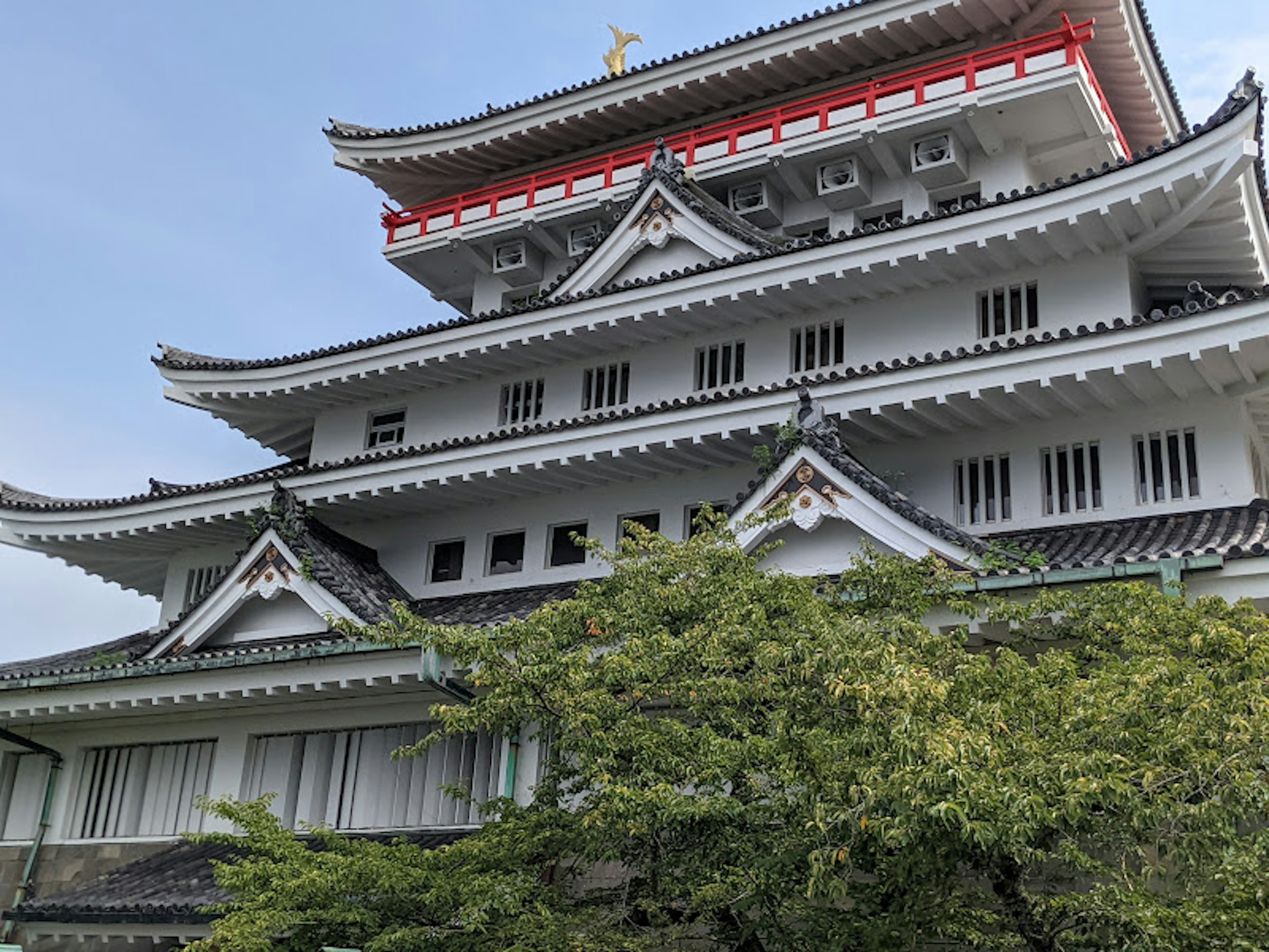 Exterior de un hermoso castillo con techo distintivo blanco y rojo rodeado de vegetación