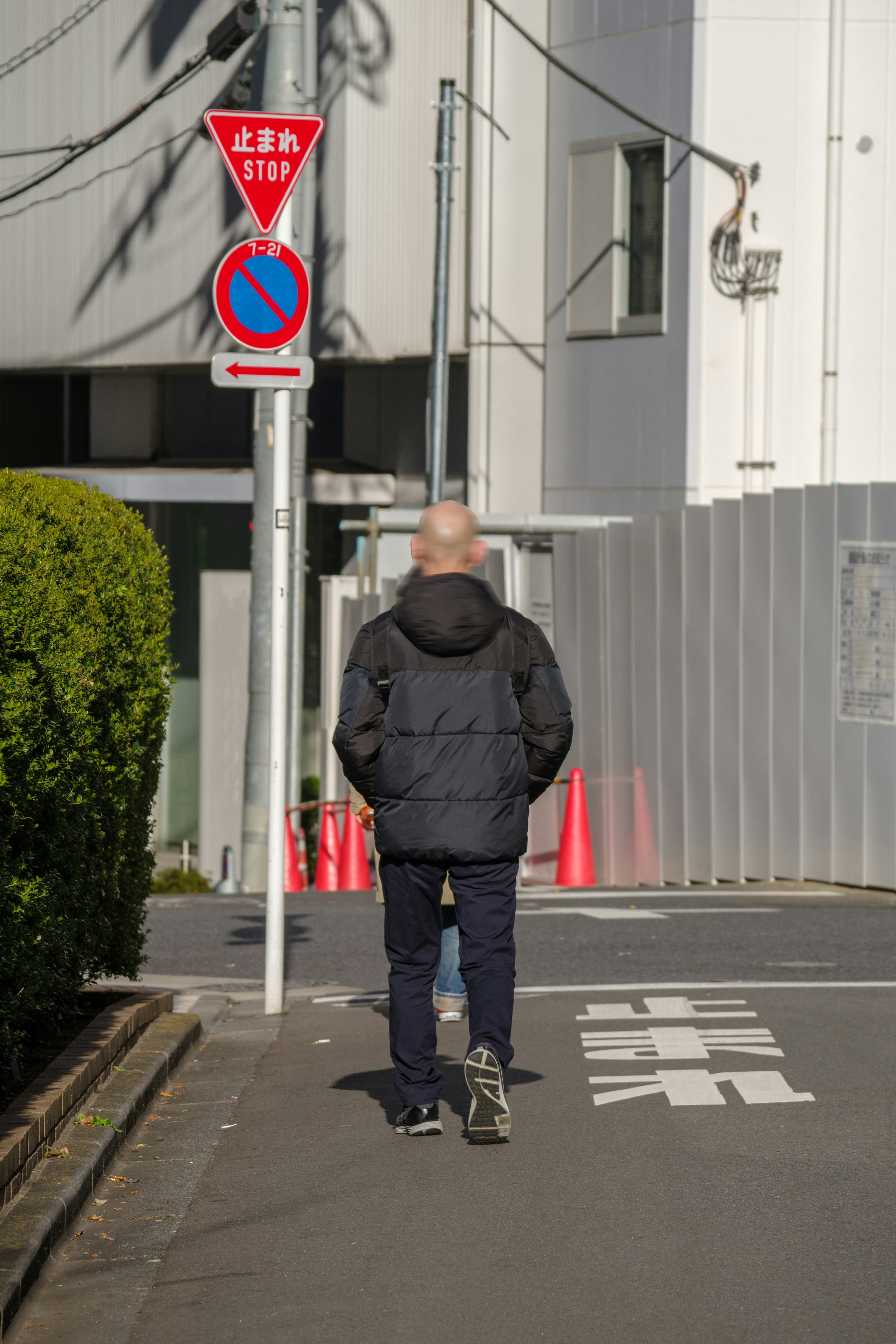 Un uomo che cammina in una strada con un segnale stradale visibile