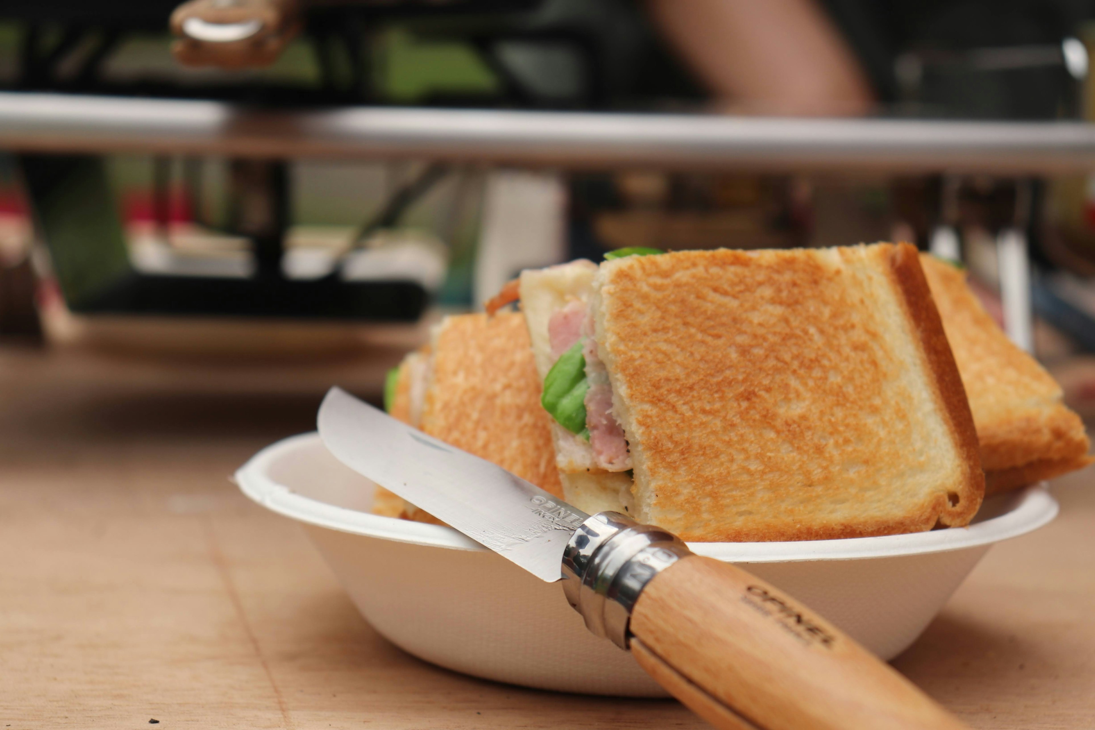 Sebuah sandwich di atas piring putih dengan pisau di sampingnya