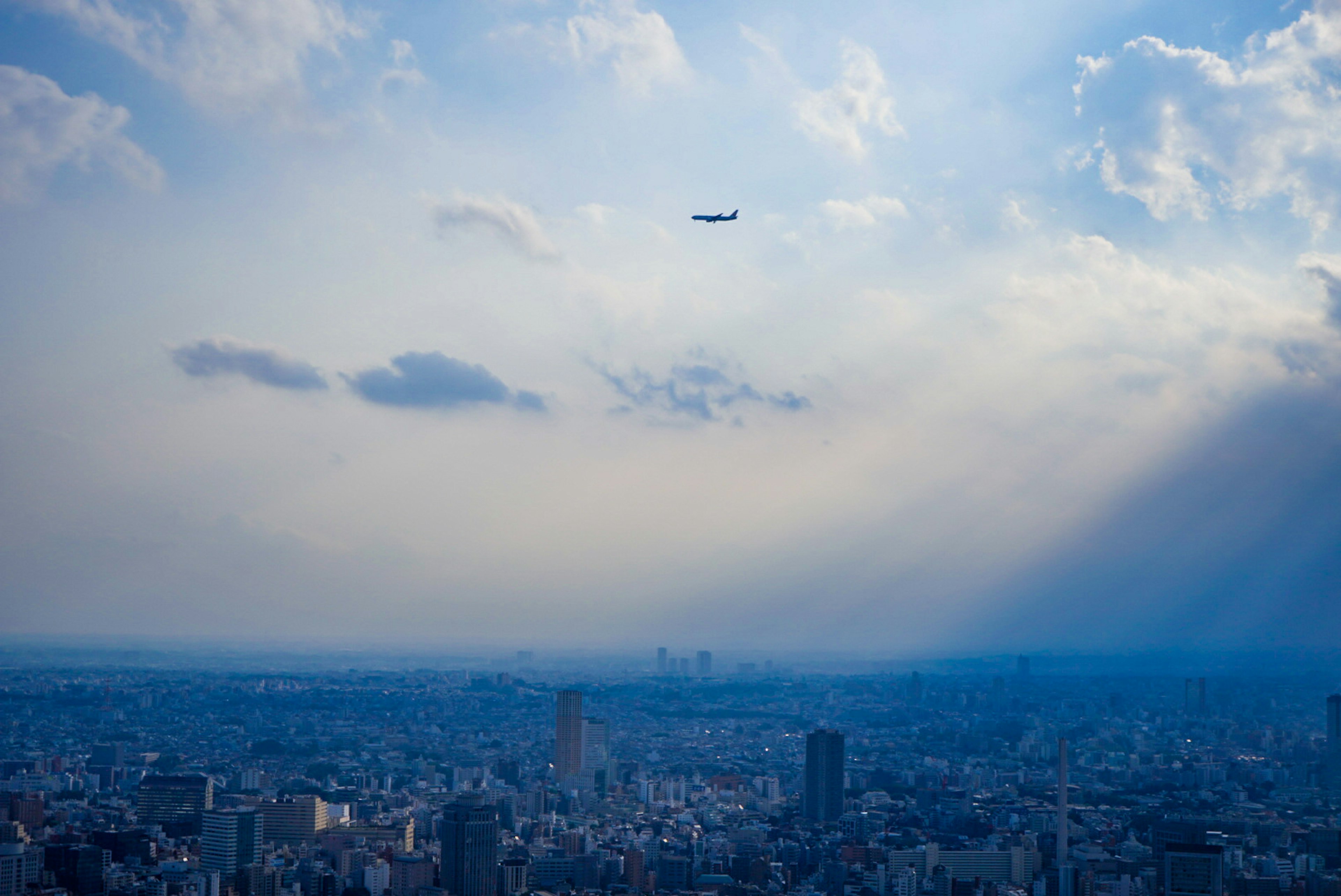 青空の下に広がる都市の景色と飛行機