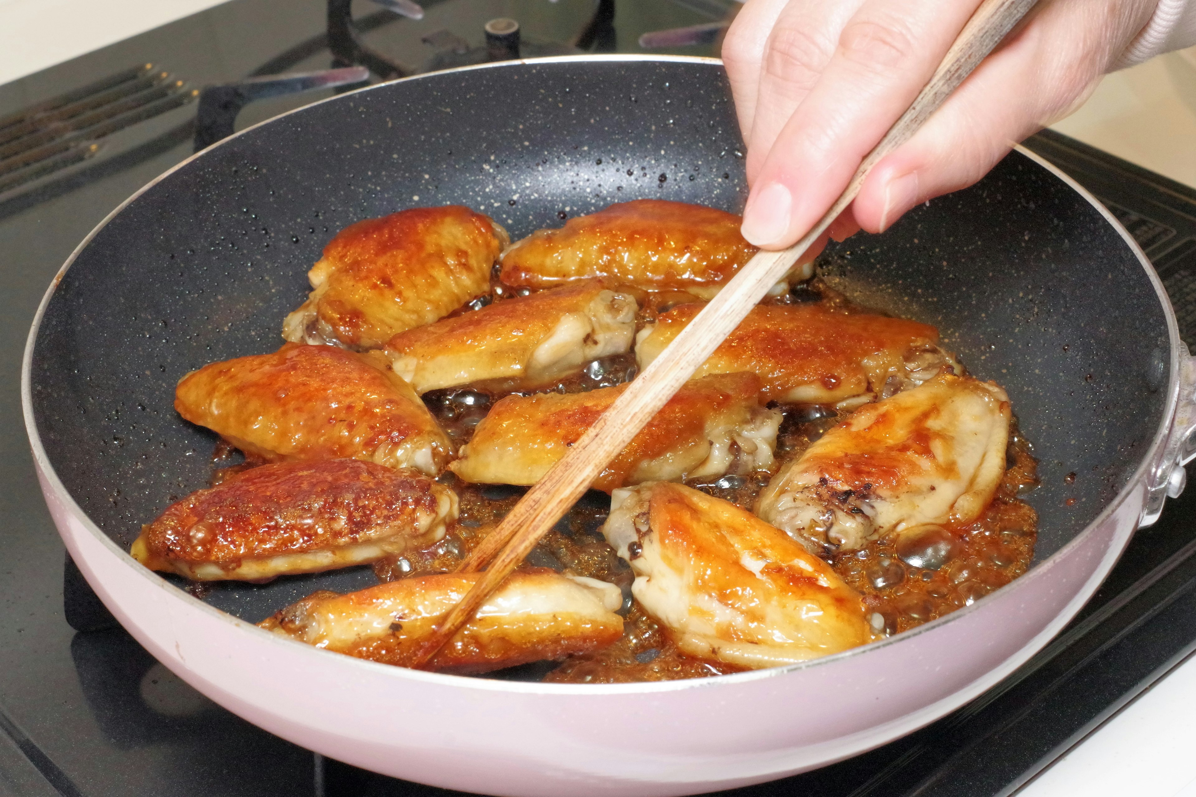 Memasak sayap ayam di wajan dengan warna cokelat keemasan