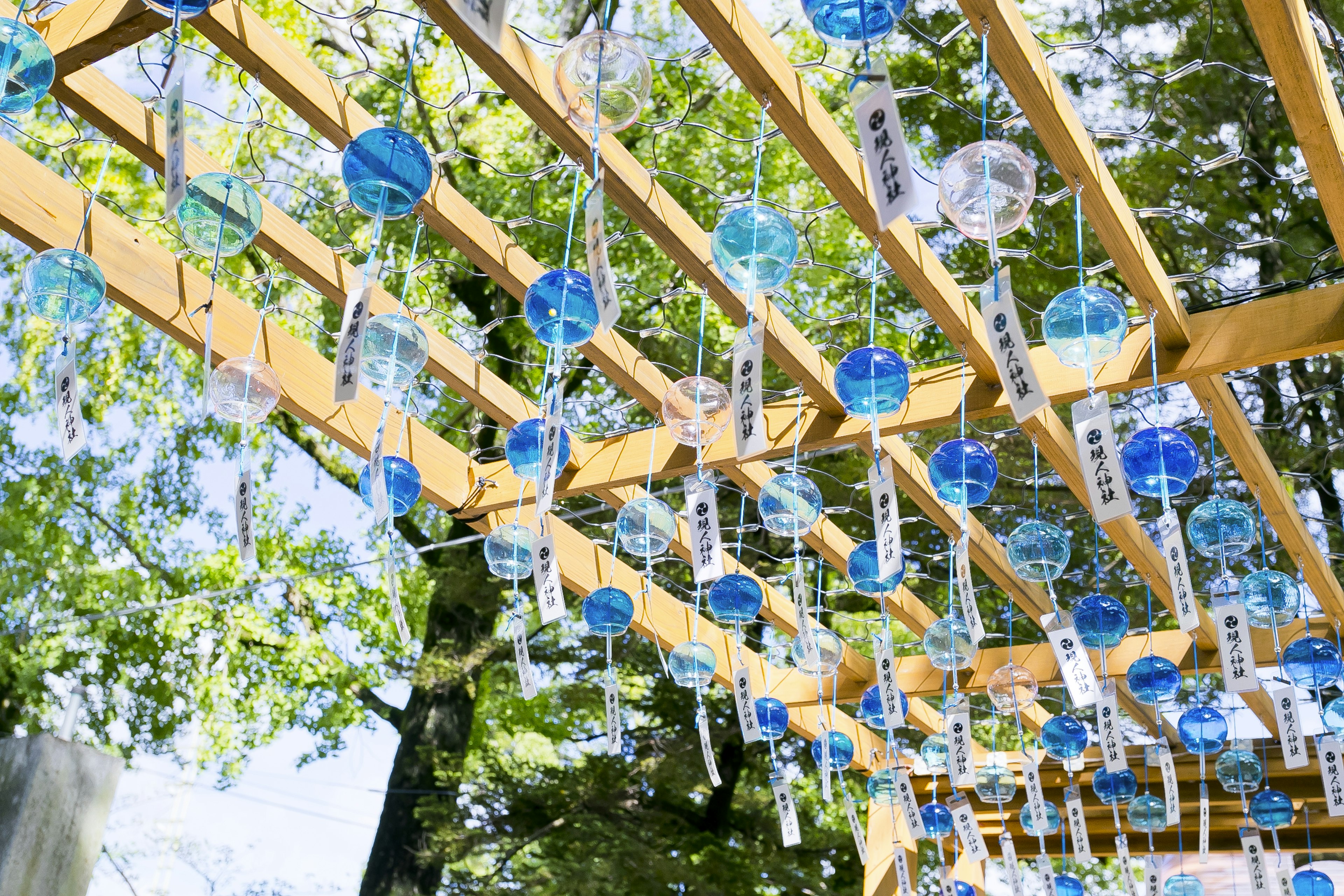 Blaue Windspiele hängen von einer Holzstruktur