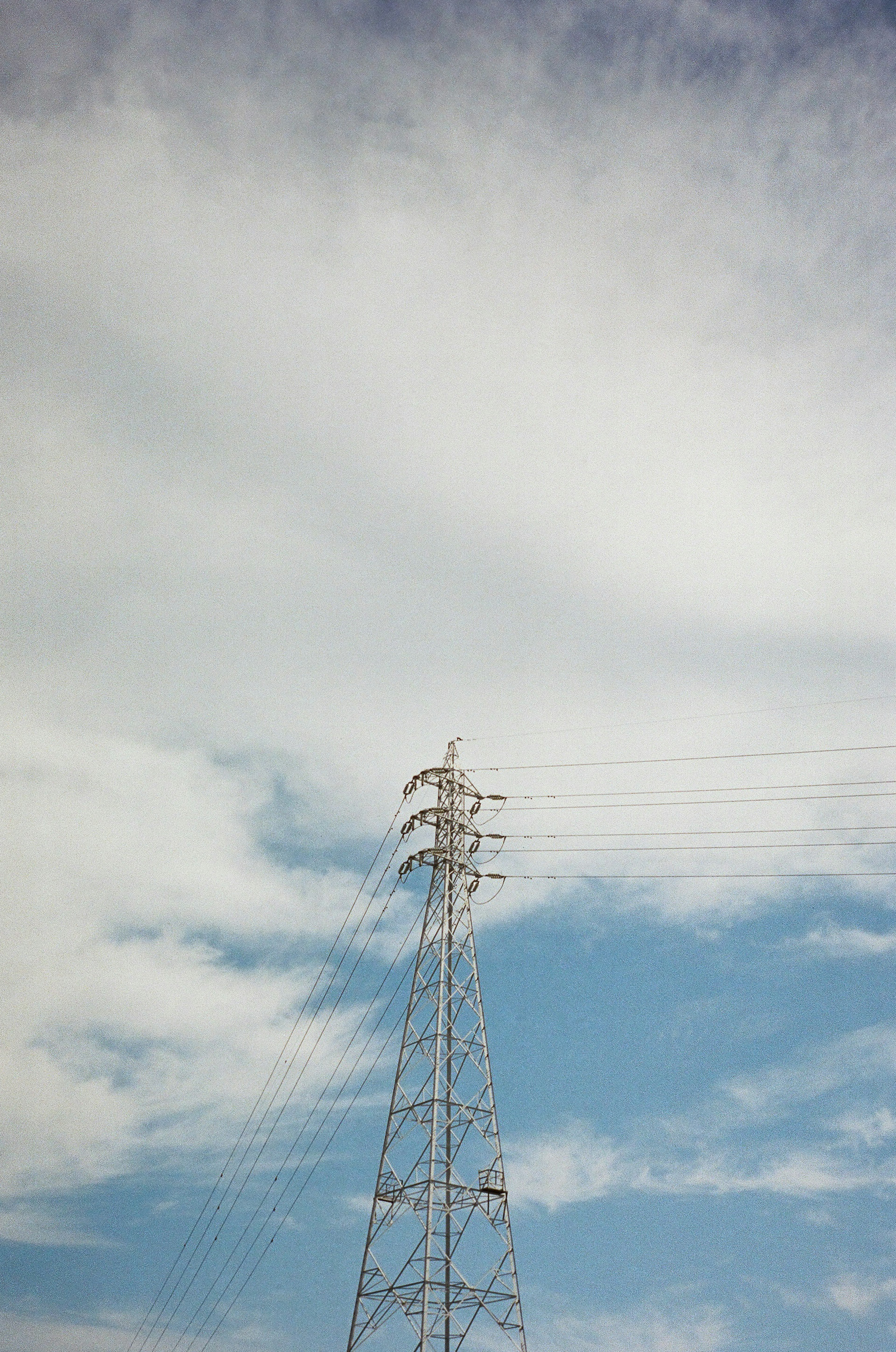 青空と白い雲の背景に立つ送電塔