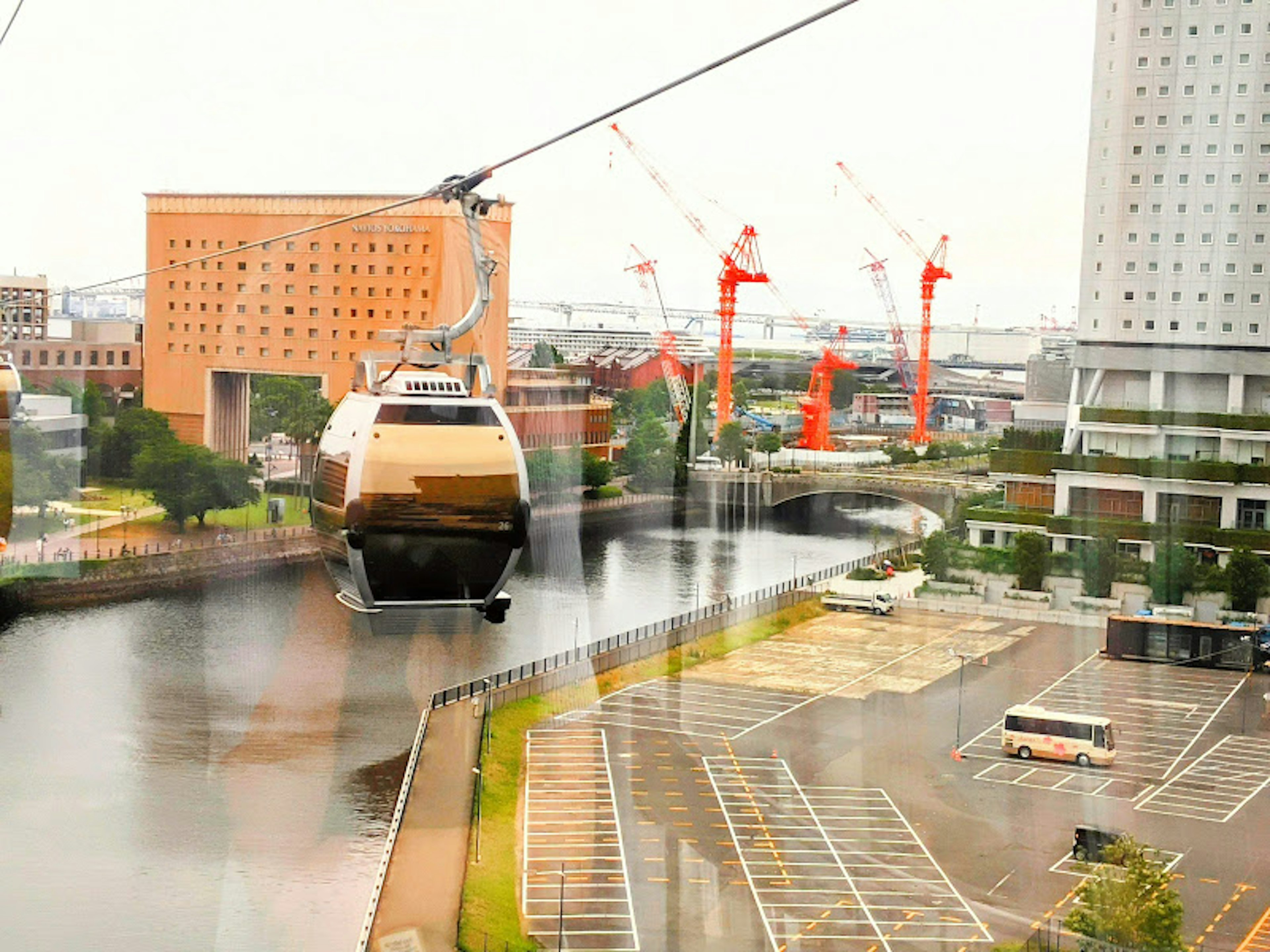 Cable car crossing a river with surrounding construction cranes