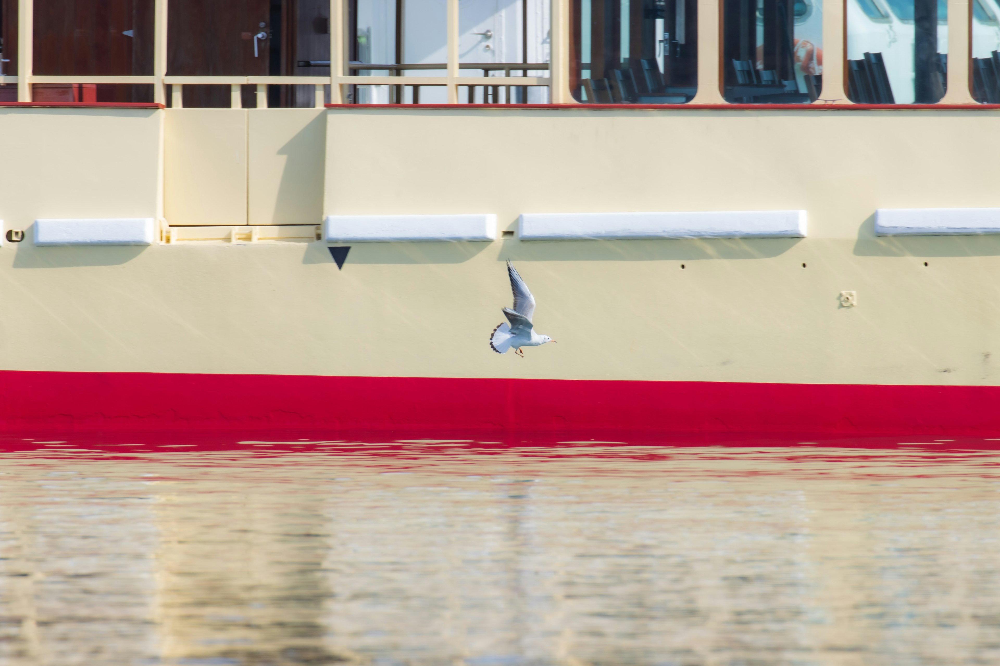 Imagen de un lado de barco amarillo y rojo con reflejo en el agua