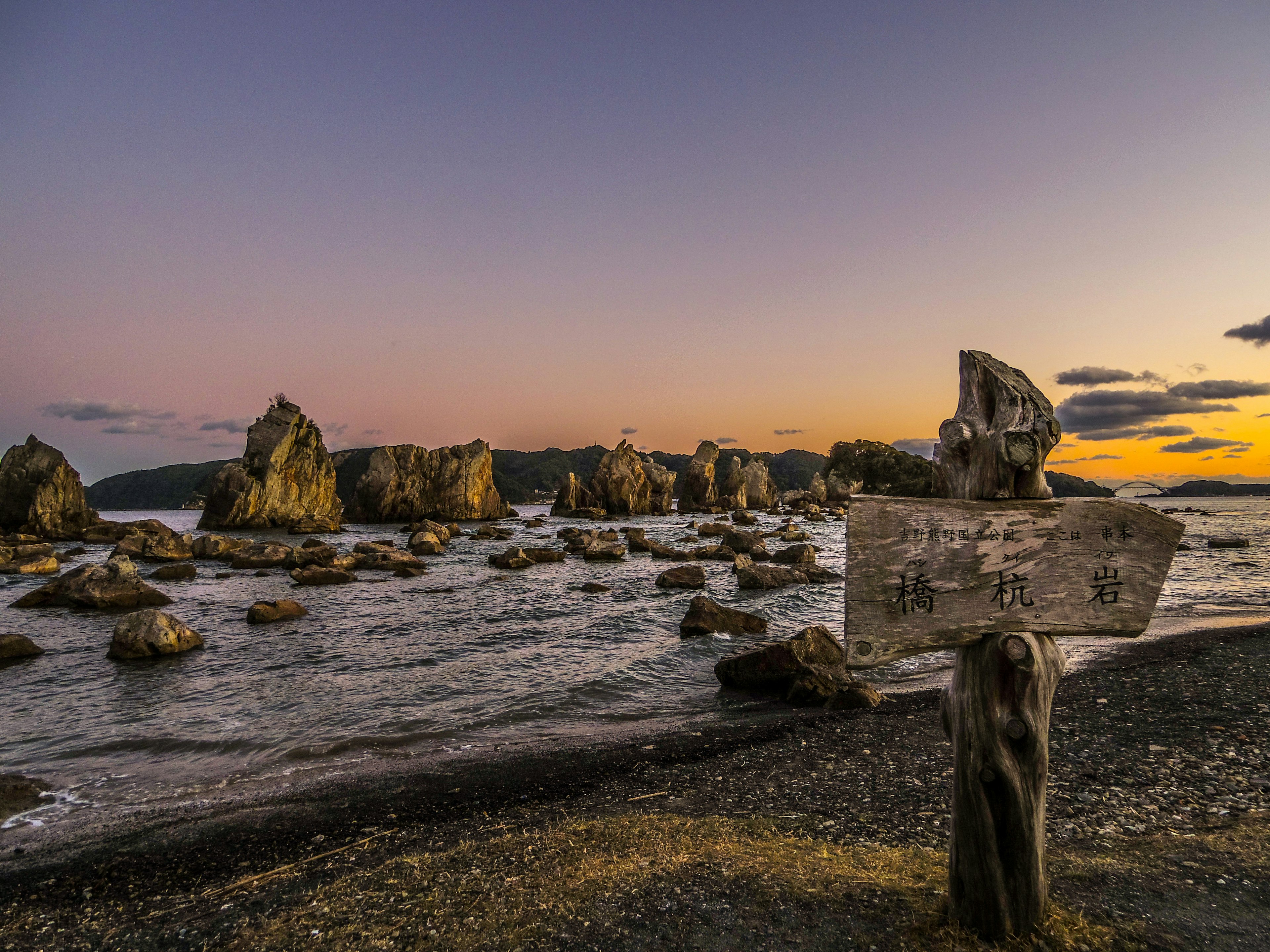 夕日の海岸に立つ古い看板と岩の景色