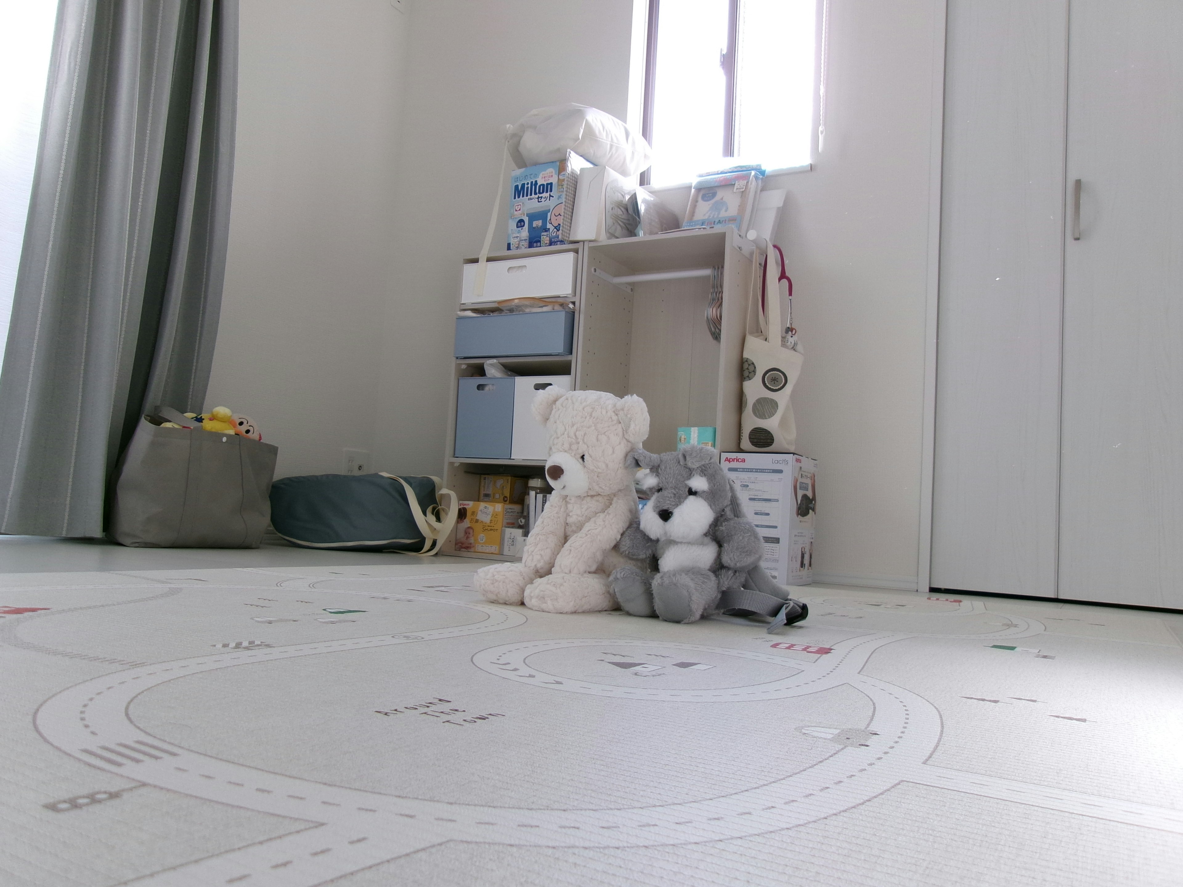 A white bear and a gray bear plush toy sitting on the floor in a room