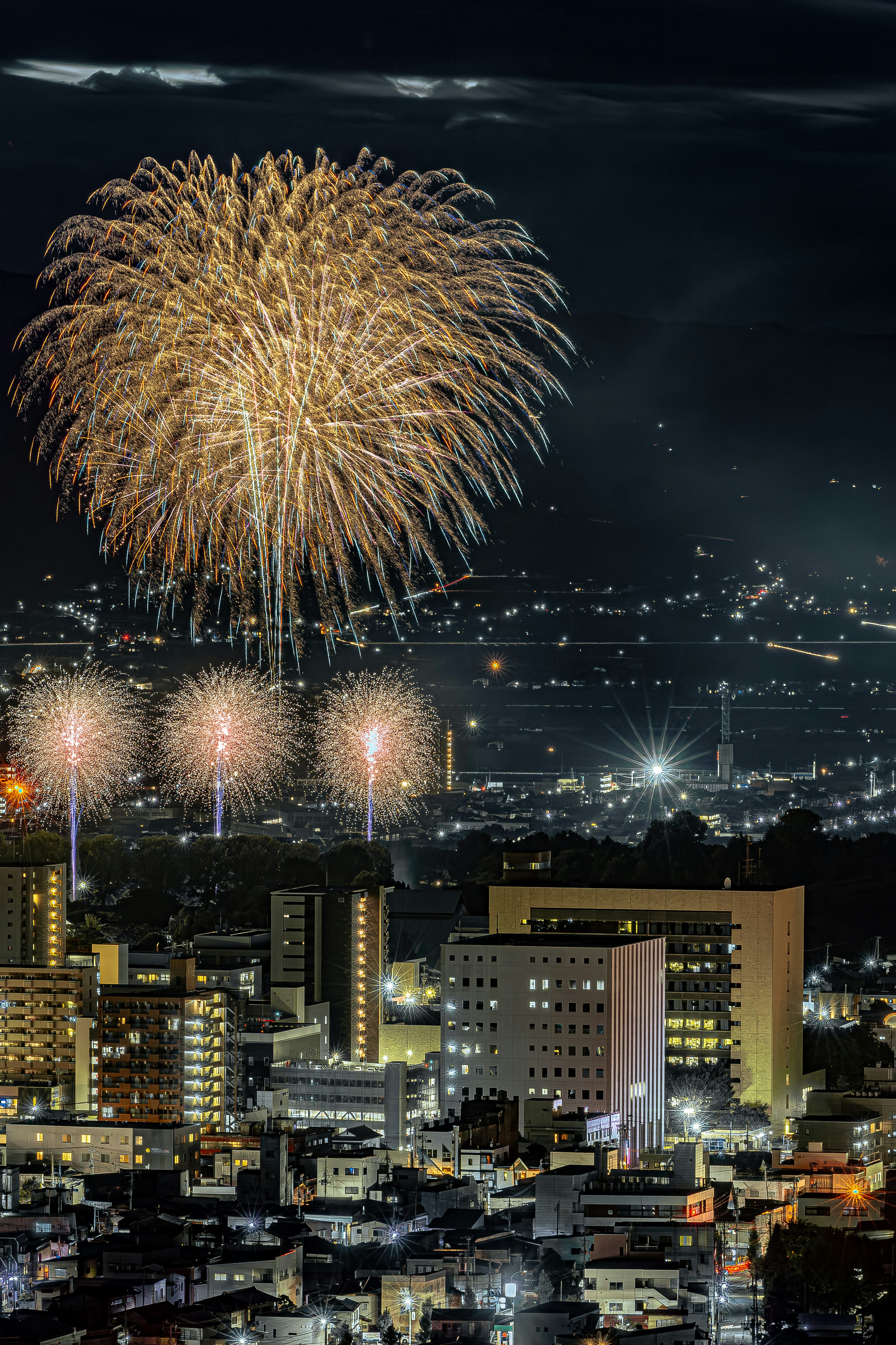 Large fireworks bursting in the night sky over a cityscape