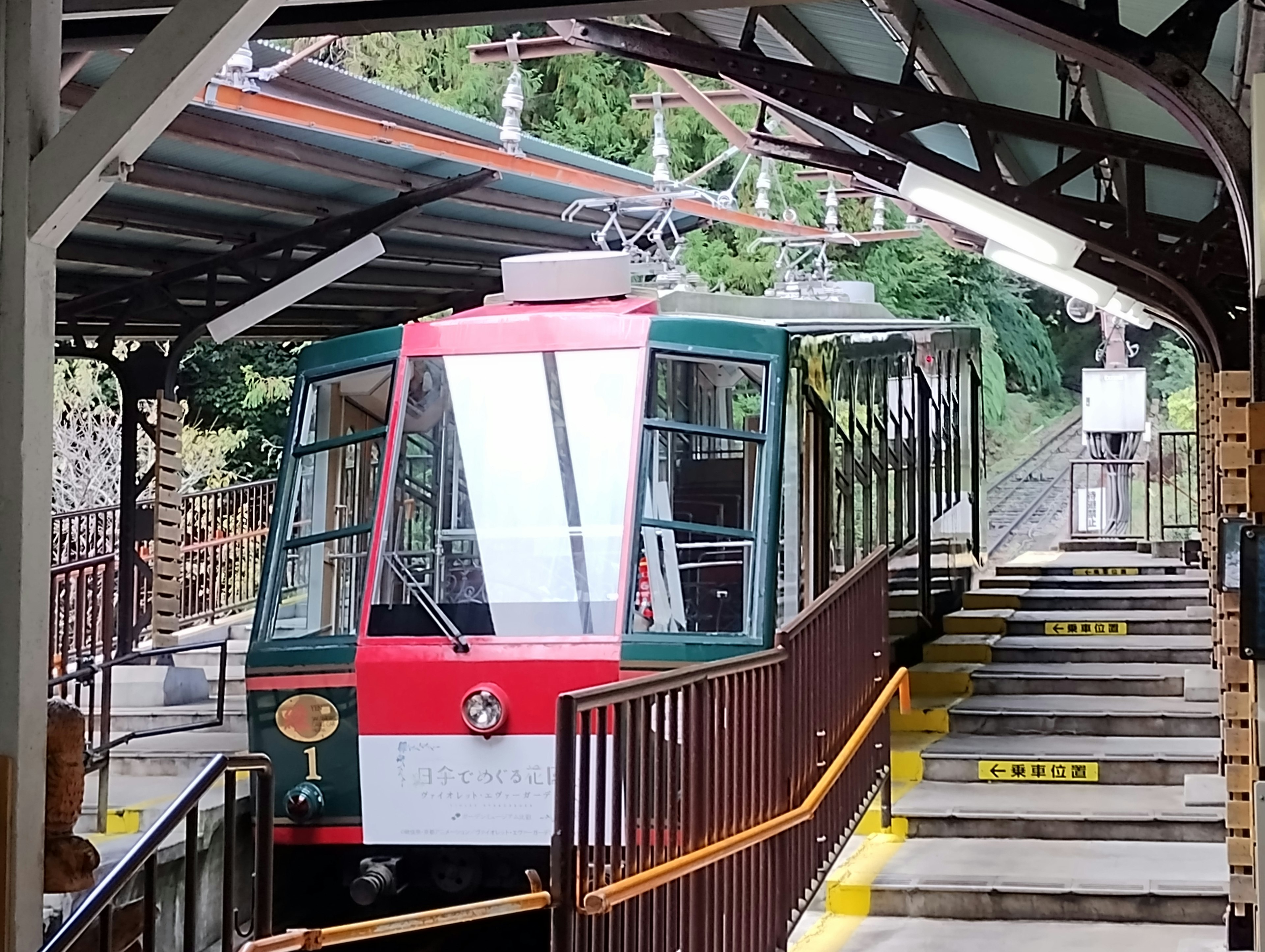 Kereta kabel hijau dan merah di sebuah stasiun