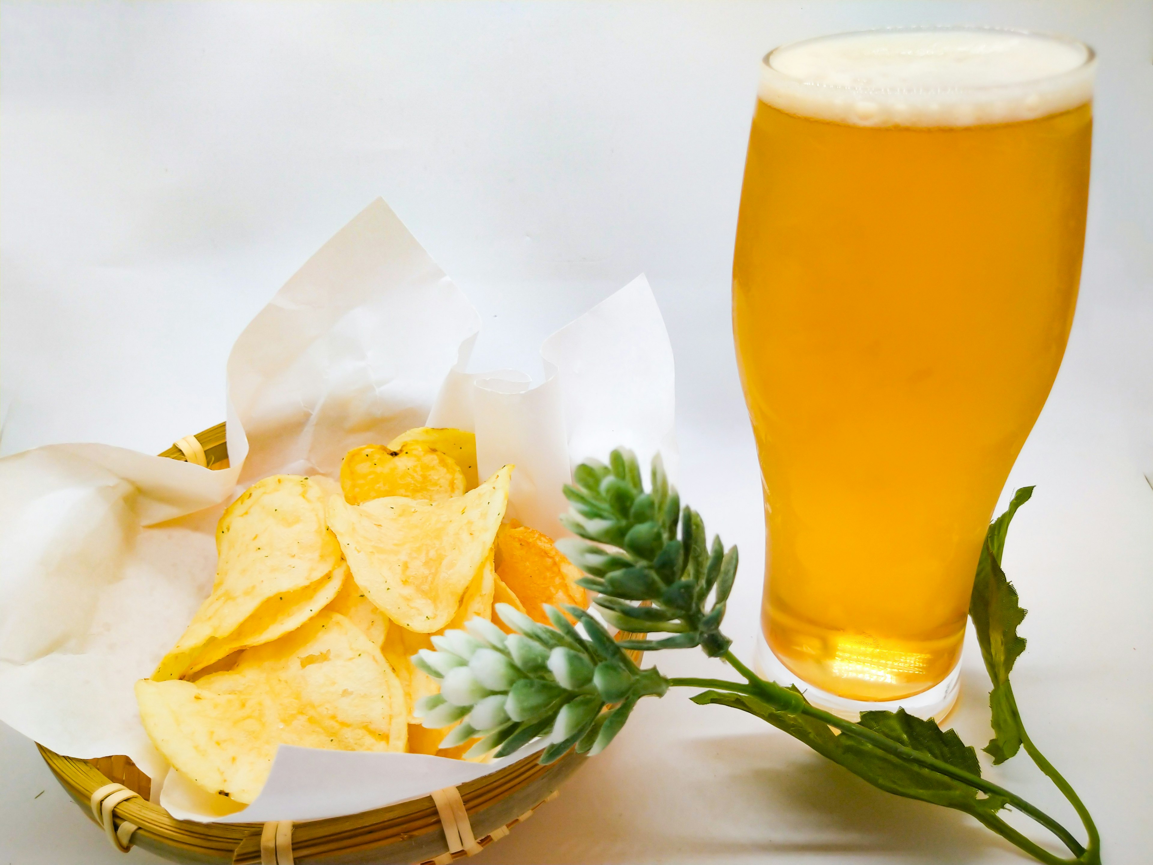 Basket of potato chips next to a glass of golden beer