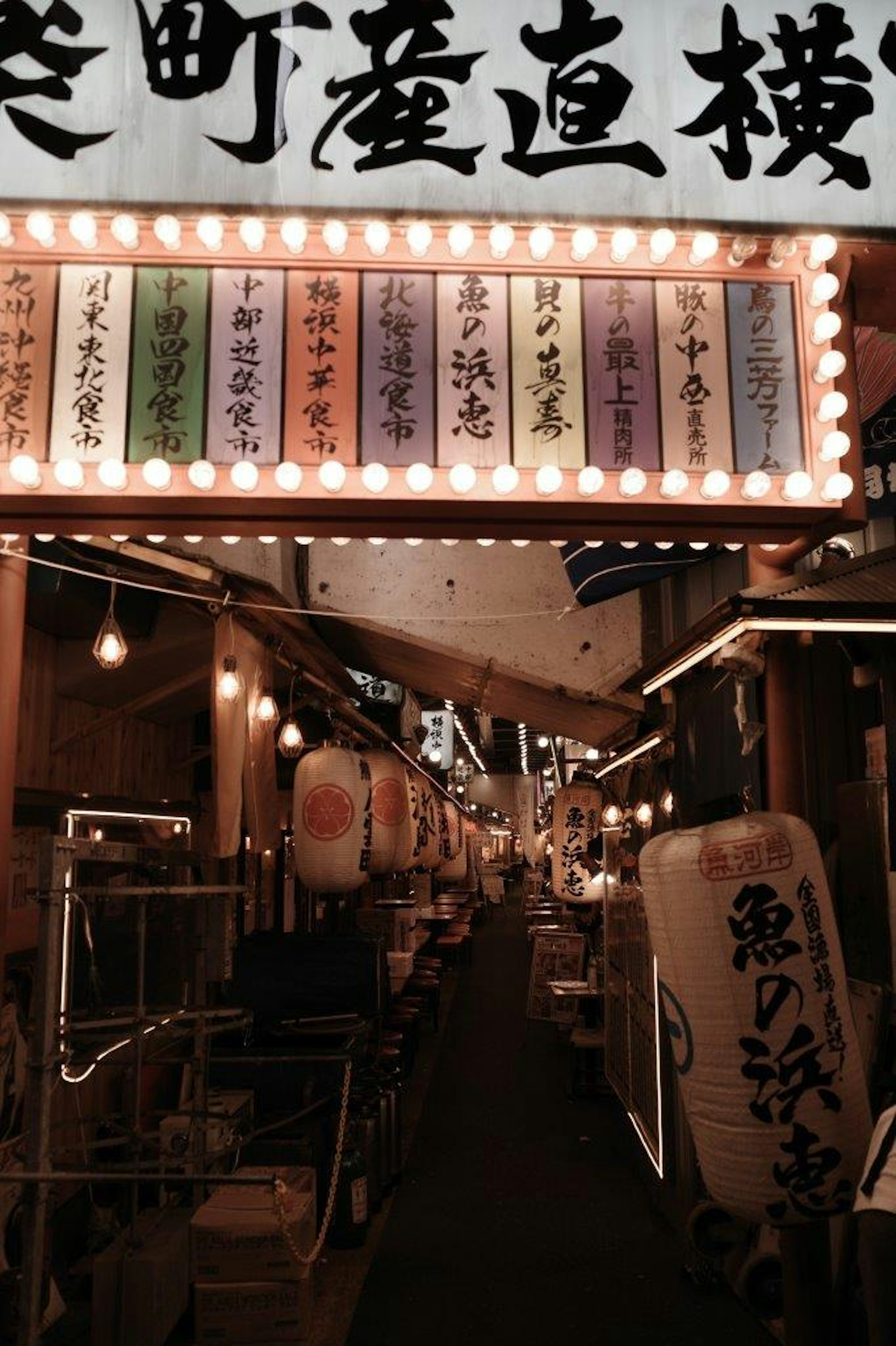 Narrow alley lined with lanterns and colorful signs in a night market