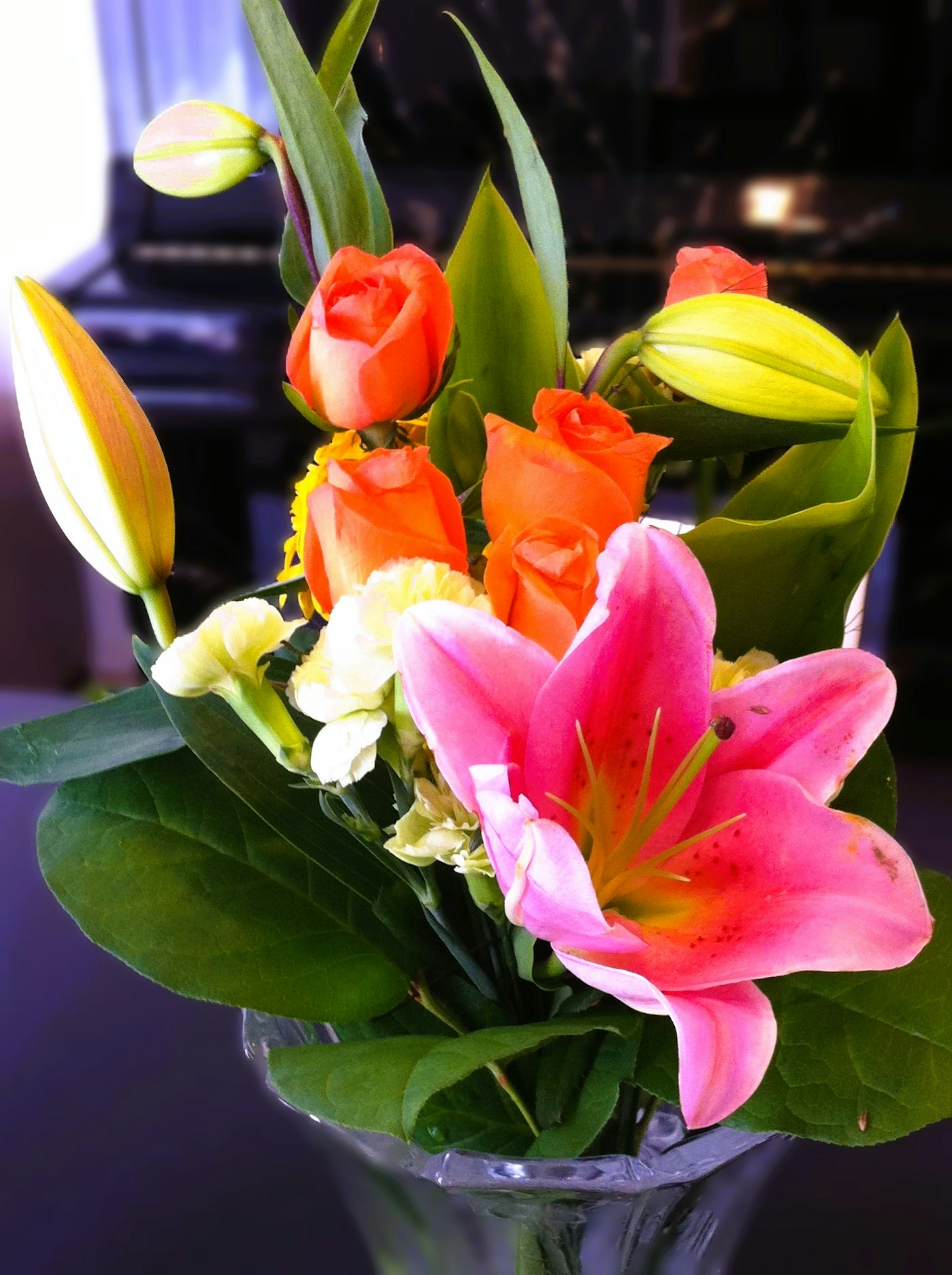 Colorful flower arrangement in a vase featuring pink lilies and orange roses